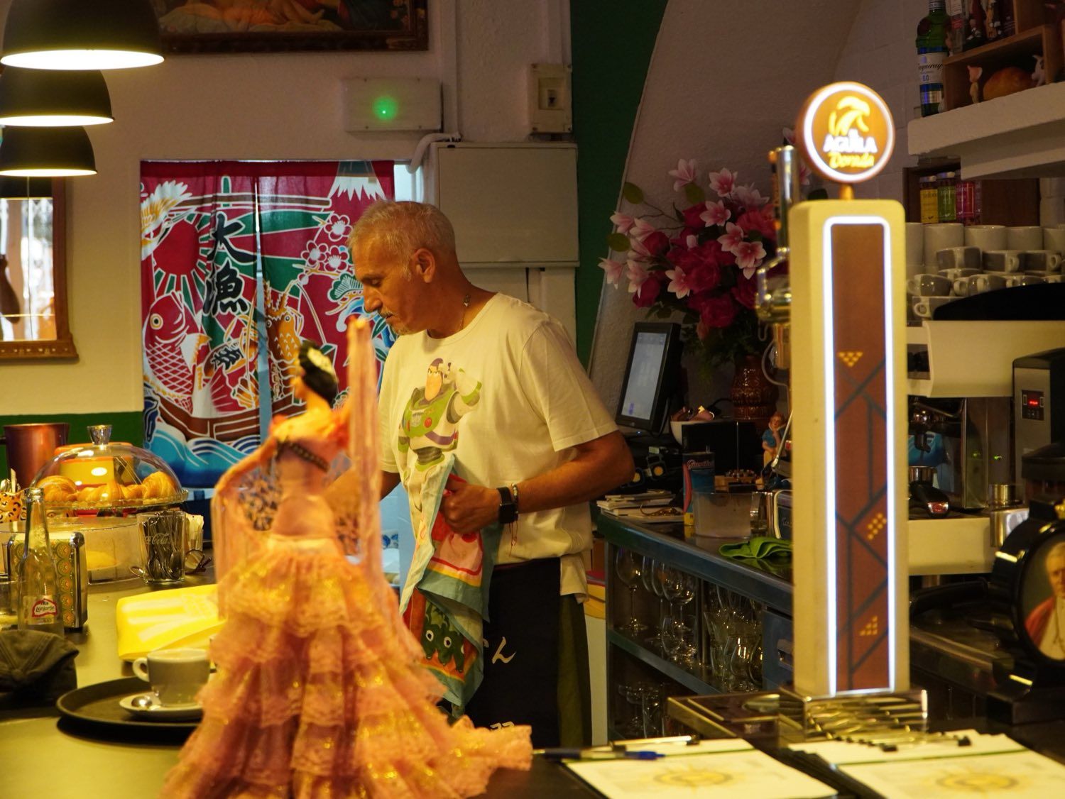 Detrás de la barra, entre figuras y flores