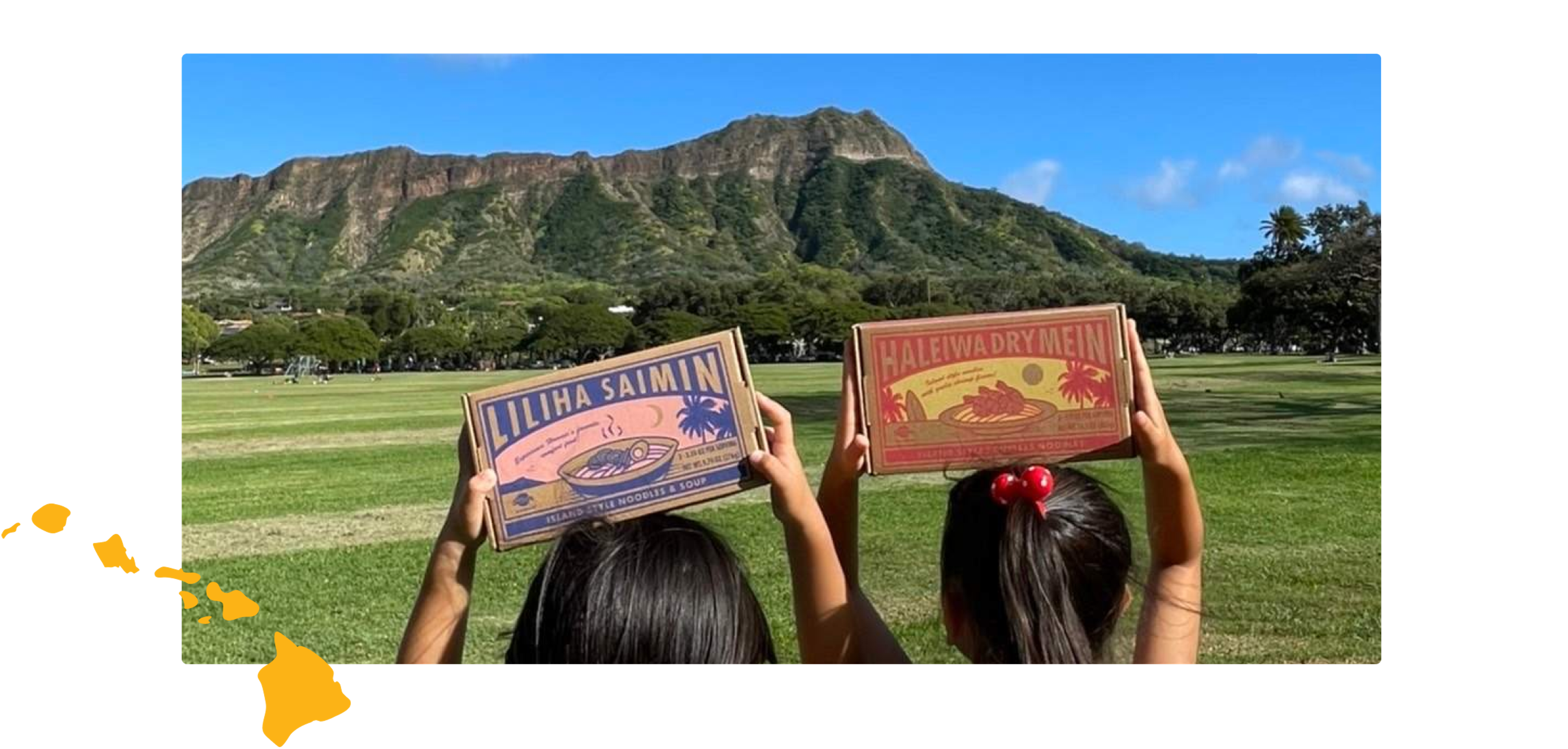 Two girls holding boxes of Liliha Saimin and Haleiwa Drymein with a postage stamp and an illustration of the island of hawaii