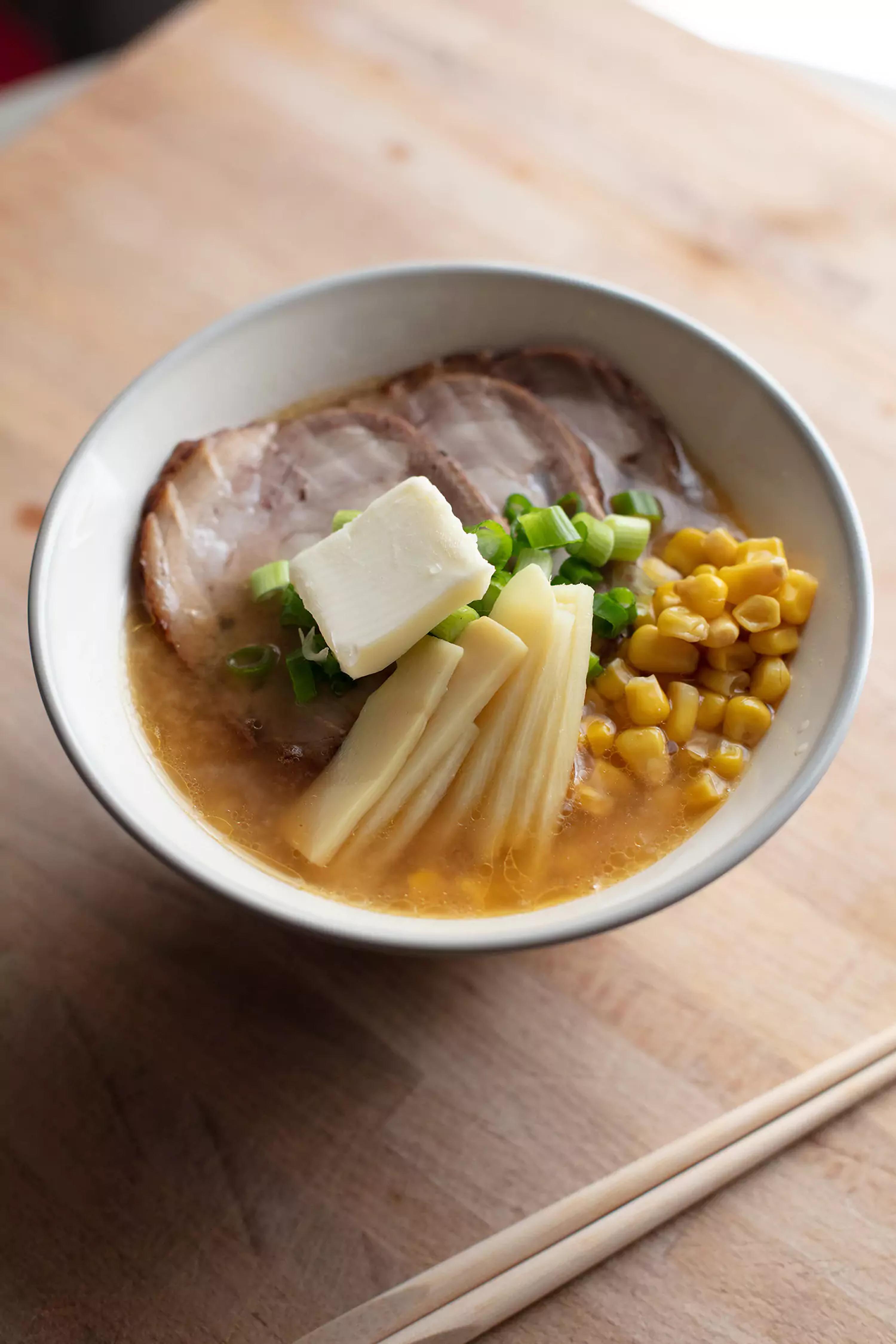 miso ramen on a bowl with some meat, cheese, corn, butter and chives.