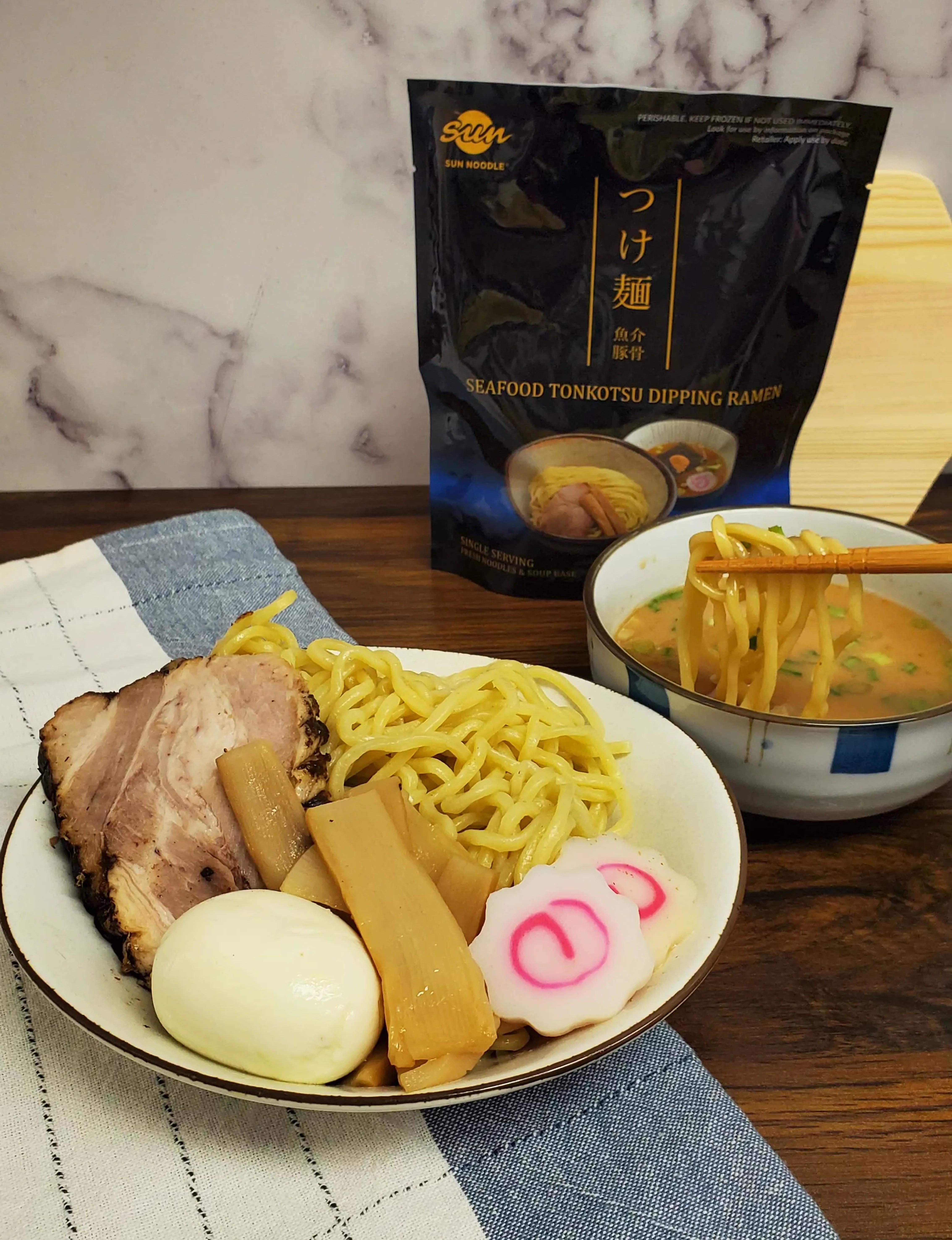 plated Seafood tonkotsu dipping ramen and noodles getting dipped on broth.