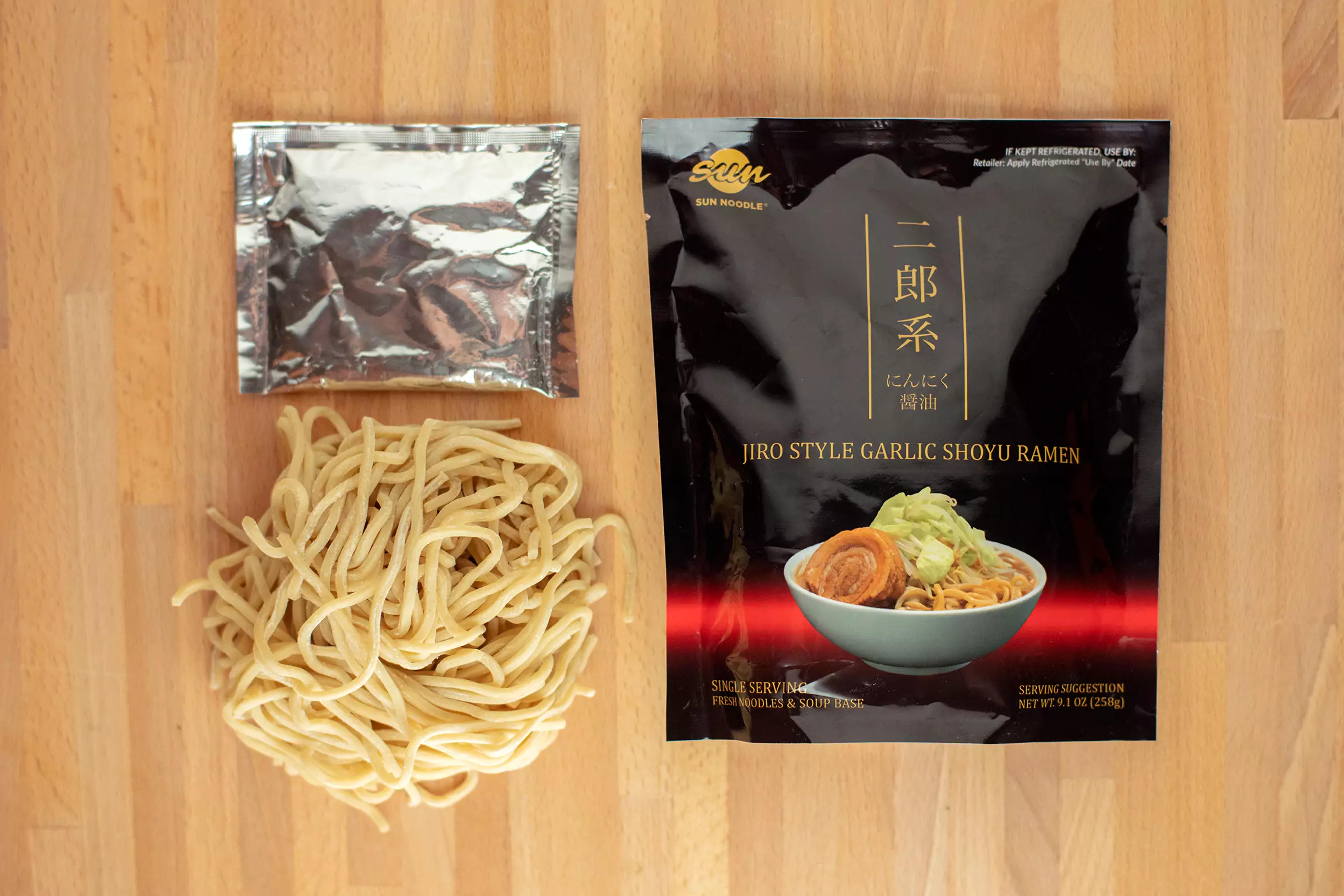 top view of Jiro style garlic shoyu ramen product packaging with the noodles and broth next to it.