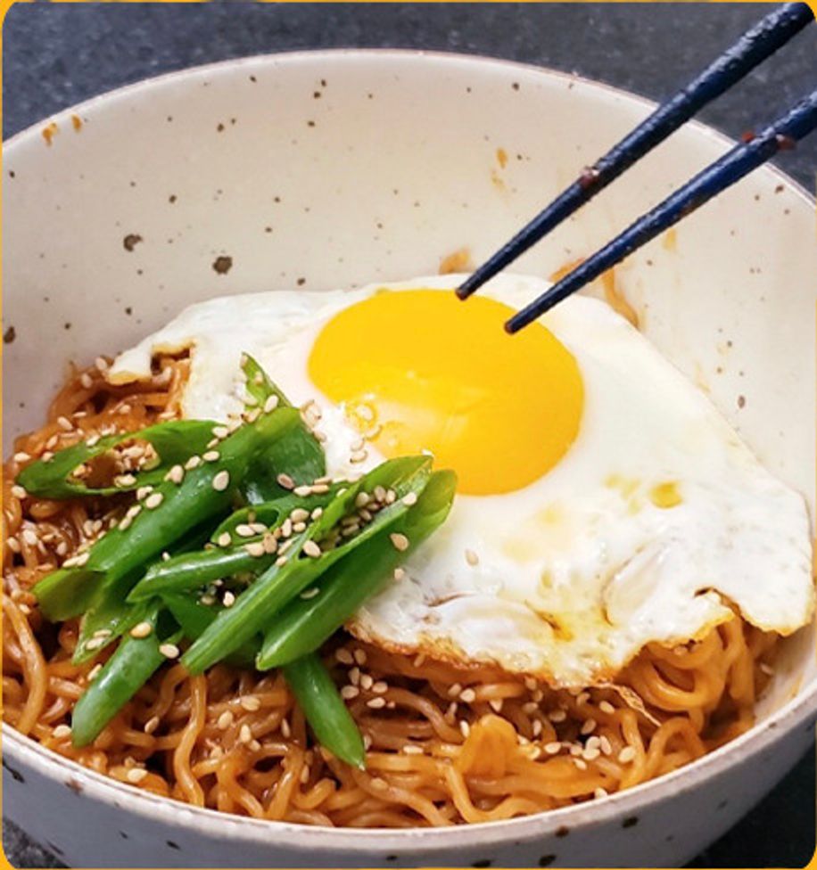 Bowl of noodles with a fried egg and green beans