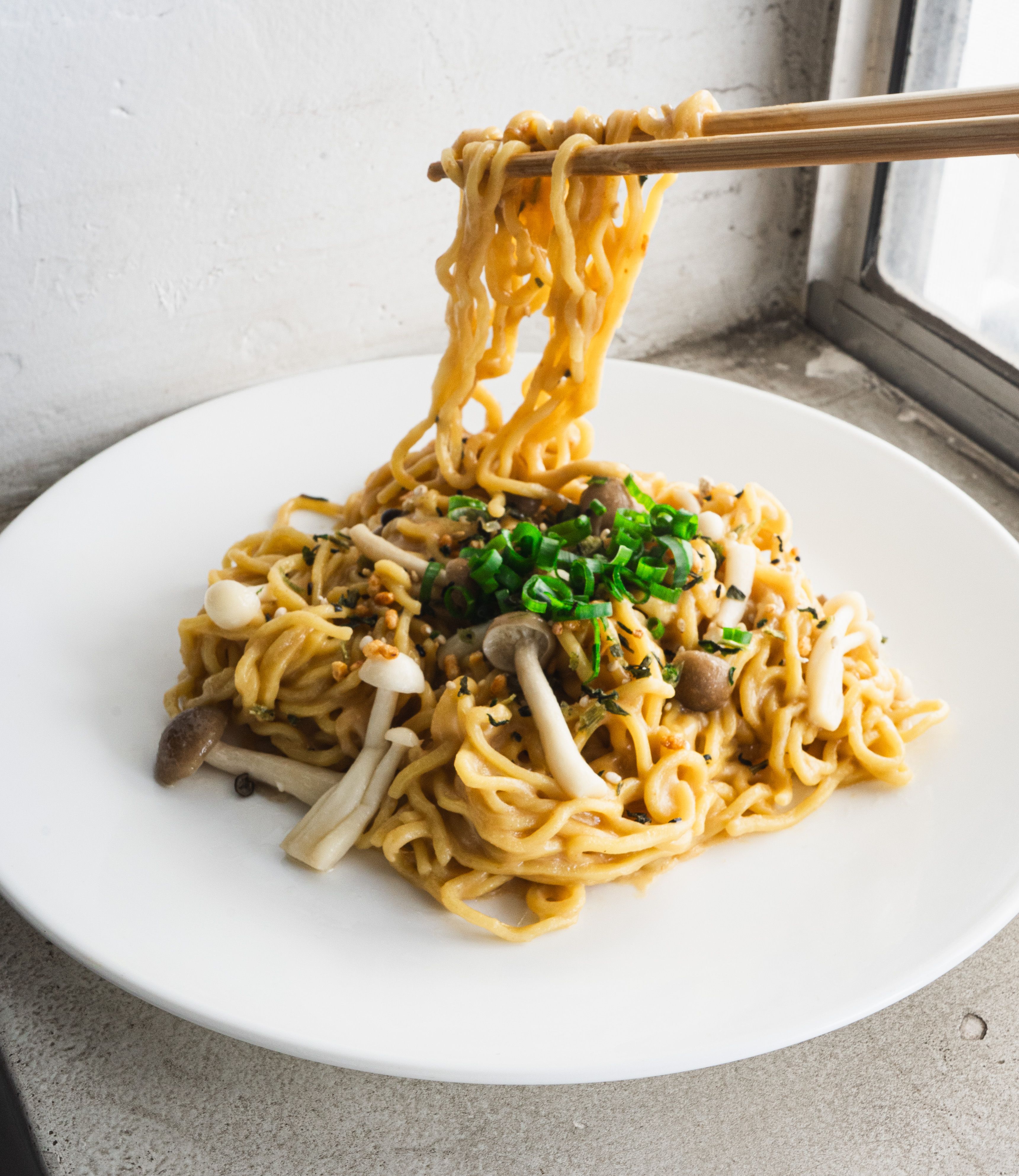 Chopsticks lifting Miso Butter Mazemen on a plate.