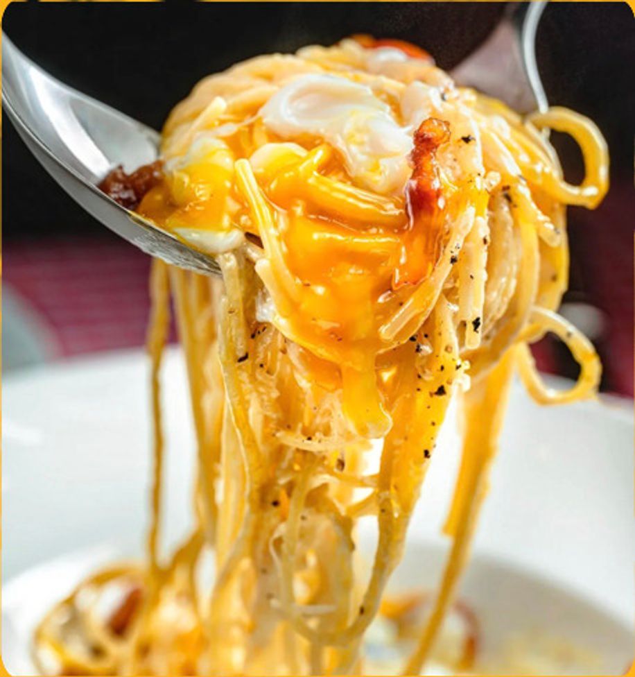 Spoon lifting creamy carbonara noodles