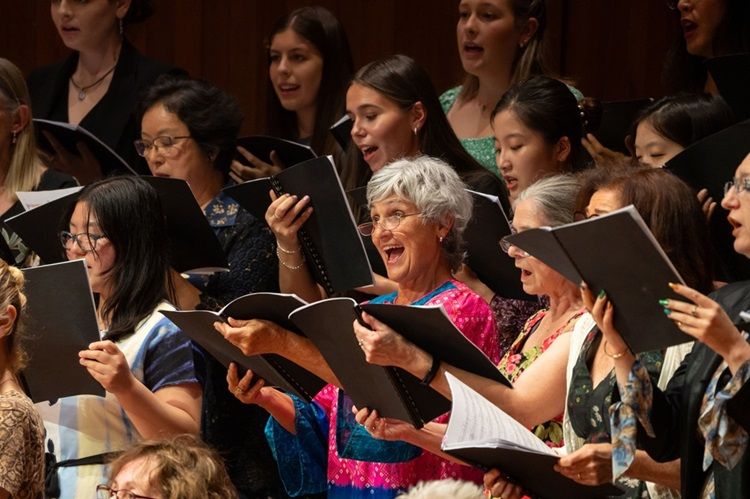 Photograph of several singers in a choir, holding their music books.