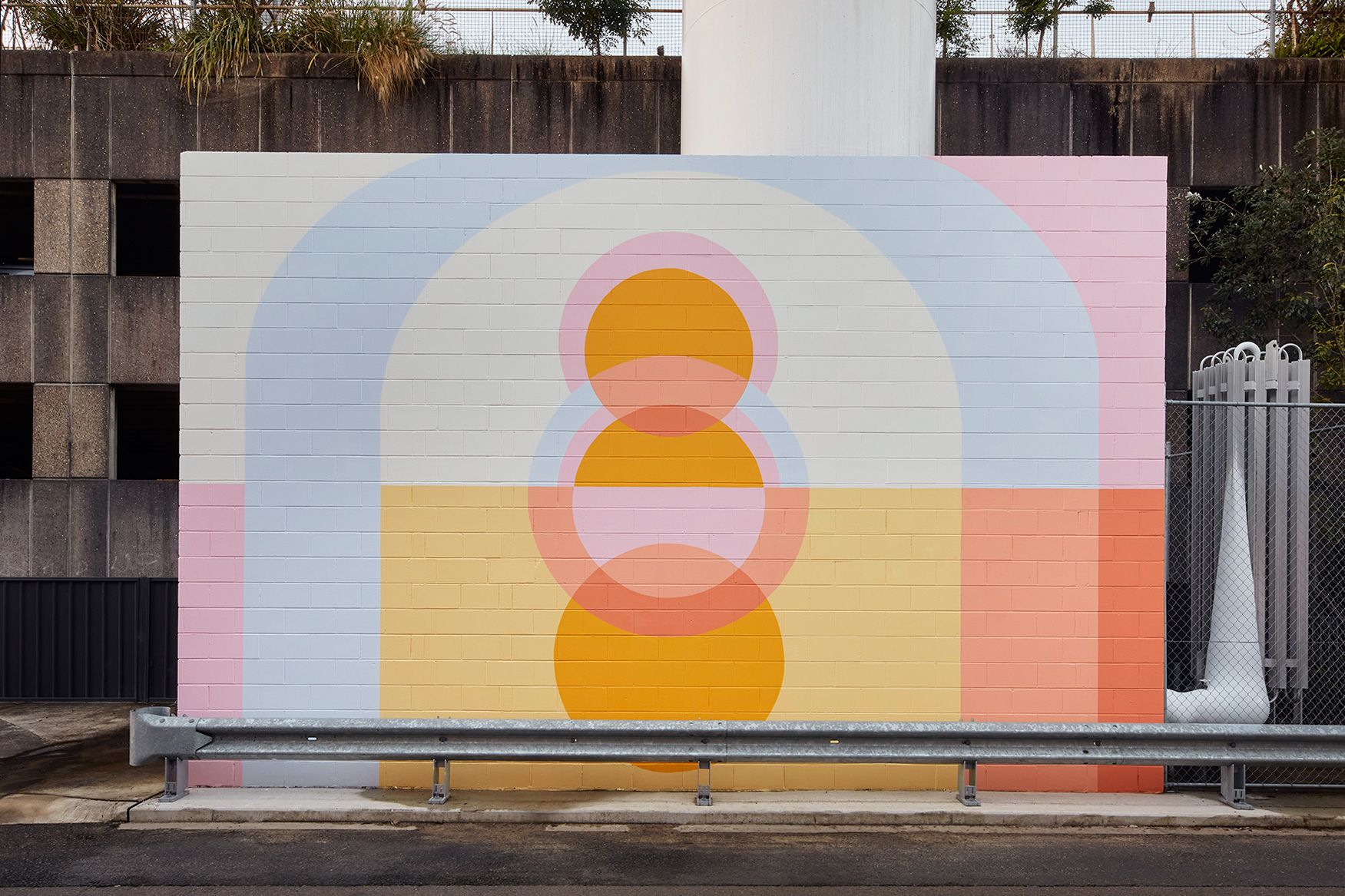 Rochelle Haley's large scale mural covers a wall along Francis Martin Drive in Randwick, the stacked circle shapes suggesting a body or a rising moon