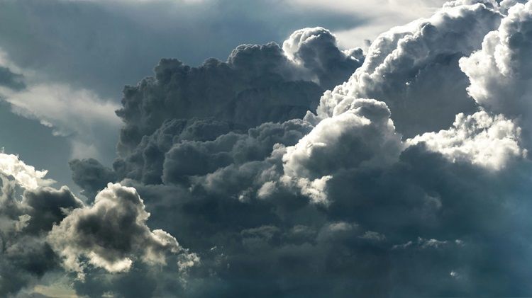 Photograph of heavy storm clouds lit by the late afternoon sun.