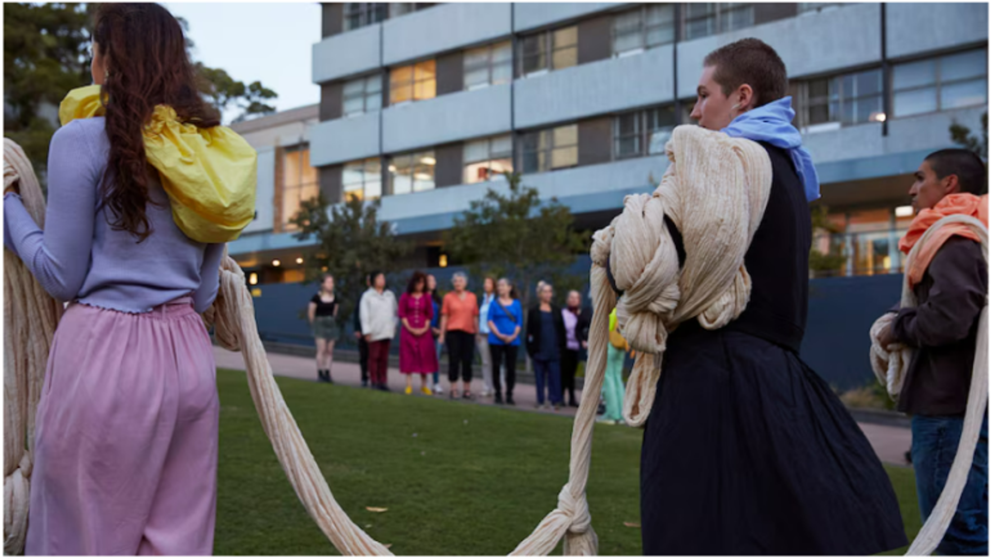 Women stand outside with ropes of cloth druing Lauren Brincat's performance work When Do I Breathe? Photo: Zan Wimberley