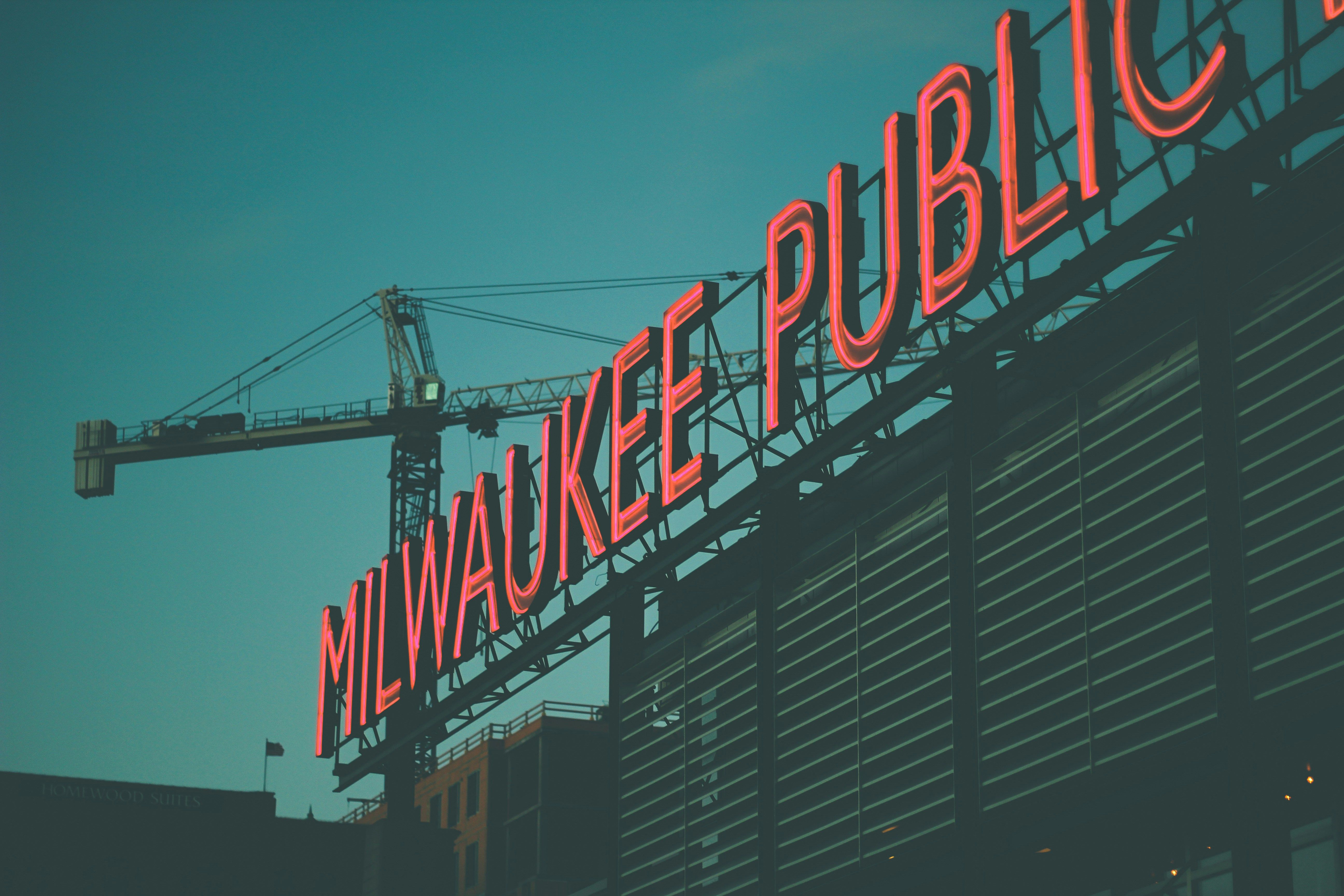 Image of Milwaukee Public Market neon sign with construction crane in background.