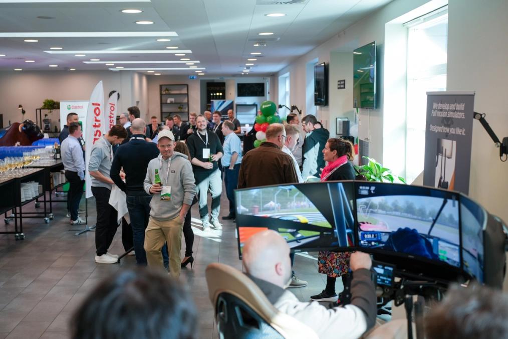 Gæster mingler ved et Castrol-arrangement med racing-simulator, balloner og Castrol-bannere