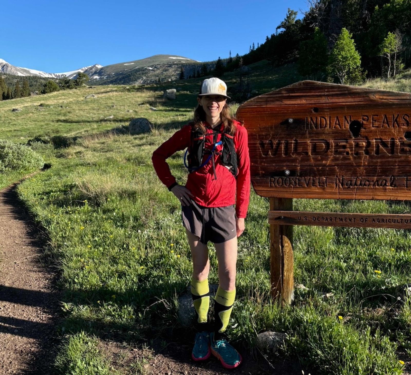 Runner in red jacket standing in front of Wilderness sign