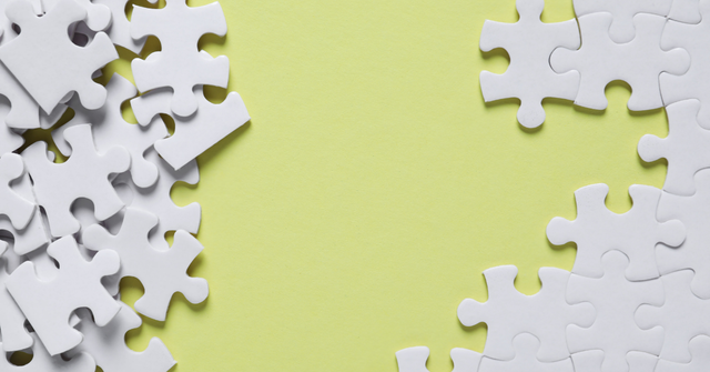 White jigsaw puzzle pieces scattered on a green background.