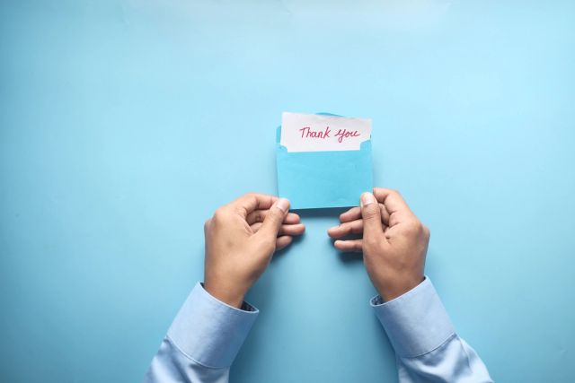 close up of man hand holding a thank you letter 