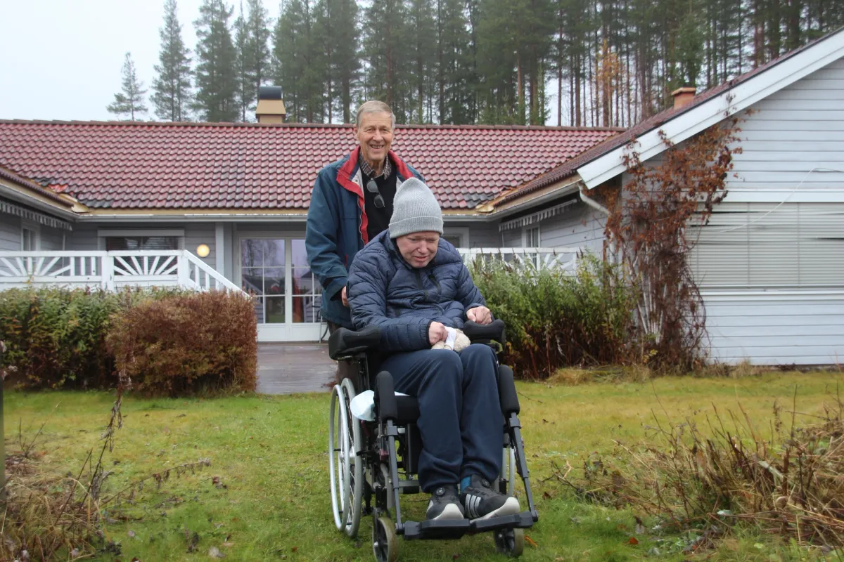 Bilde av mann i rullestol, Egil Andre, sammen med pappa, Ole Edvar, foran boligen.