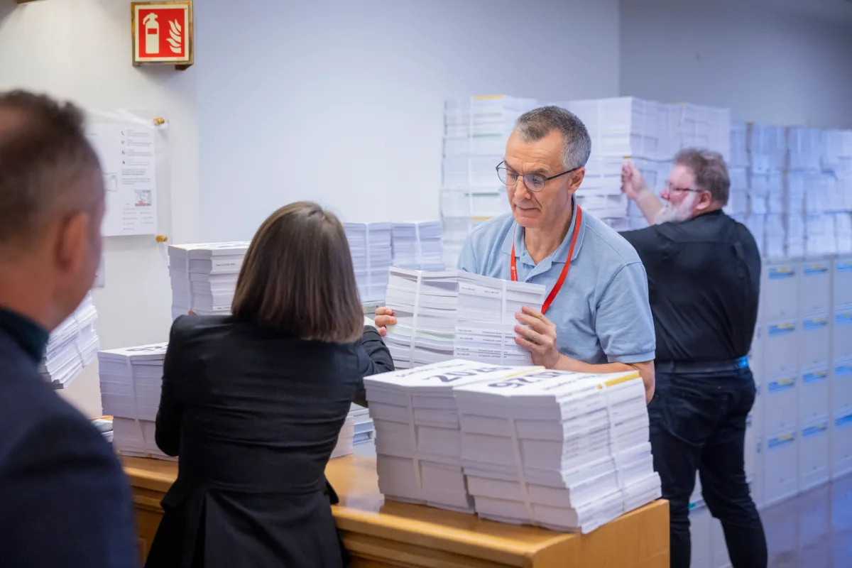 En mann henter en tykk bunke med papirer.