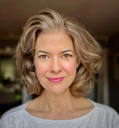<A woman with medium-length light brown hair smiles with a blurred background.>
