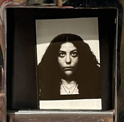 <A black and white image of a woman looking upward with a plain background. She has long curly black hair.>