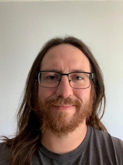 A photo of Andrew Kozlowki smiling on a white backdrop. 