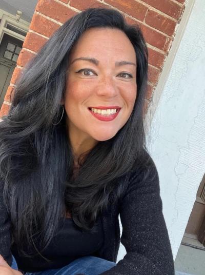 Photo of Joan Kwon Glass smiling in a black top and jeans. 