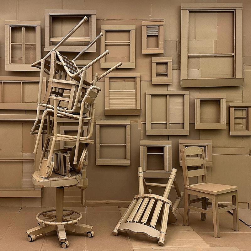 Photograph of art installation that features a room full of windows and chairs all made out of cardboard. 