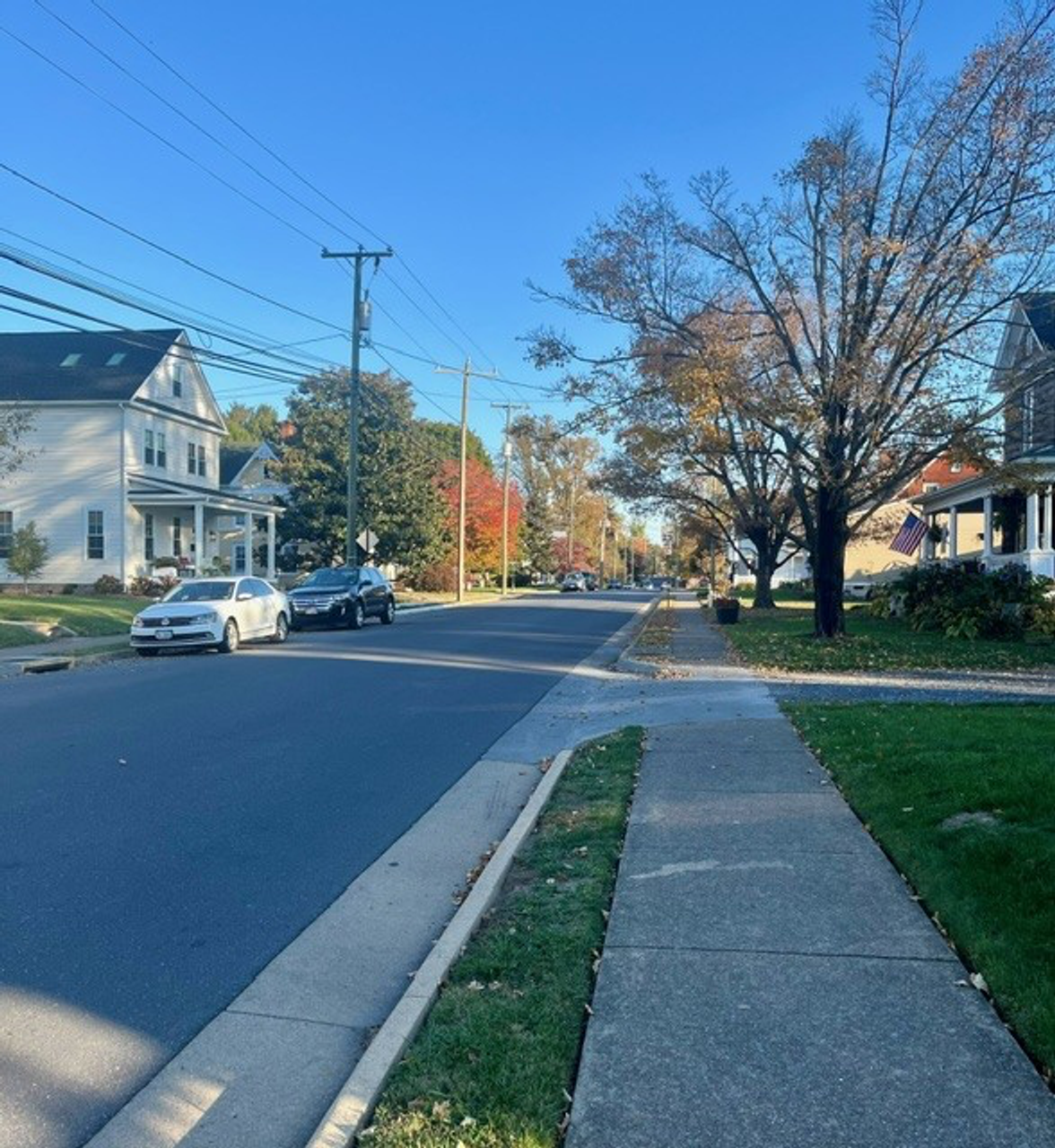 small town street showing sidewalk, power lines and cars
