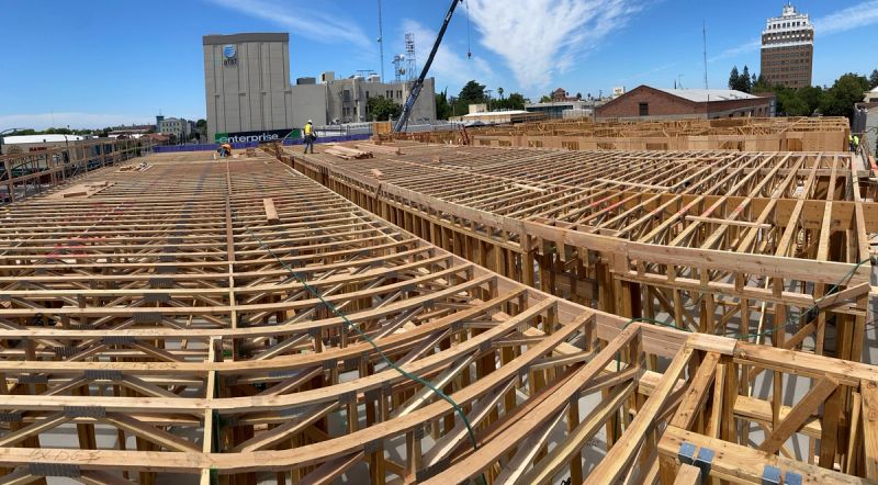 Panoramic view of open-web floor trusses spanning a large commercial construction project with a crane and Sacramento skyline in the background by Mike Walker Lumber Co Inc