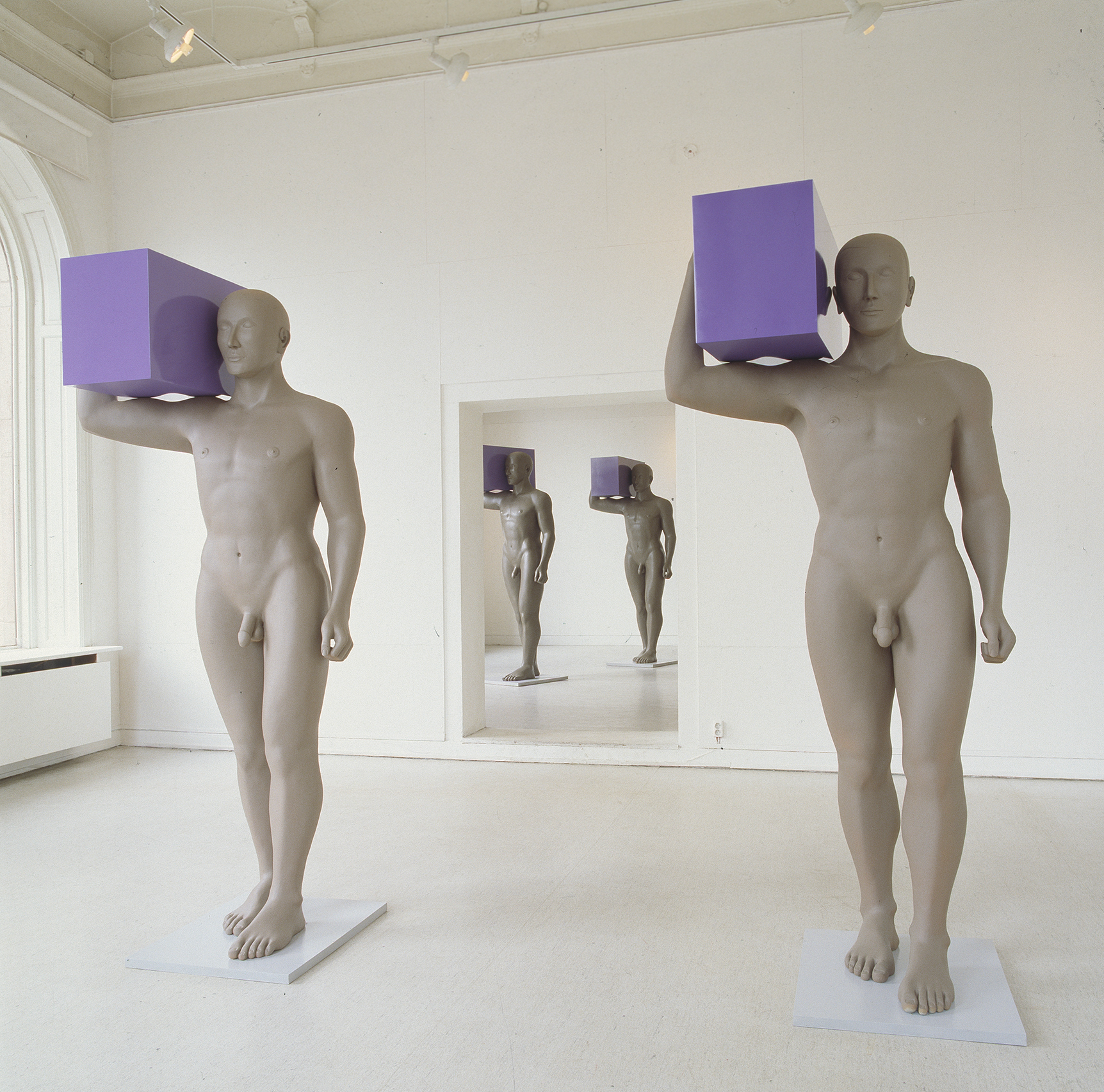 Four sculptures of men holding purple boxes