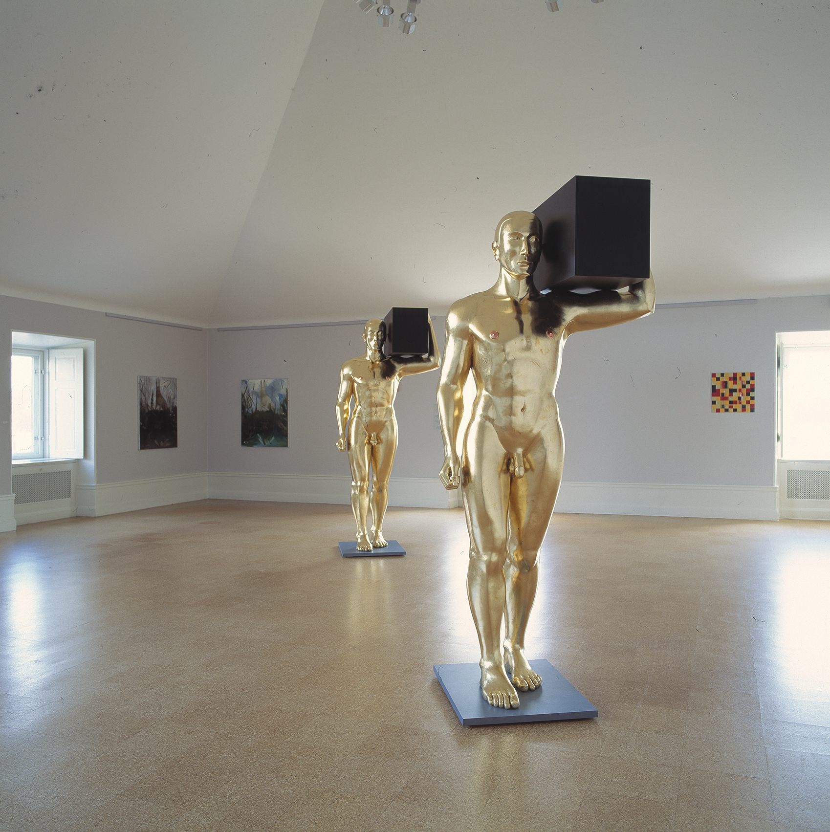 Two sculptures of a golden man holding a black box