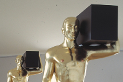 Two golden sculptures of a man holding a black box