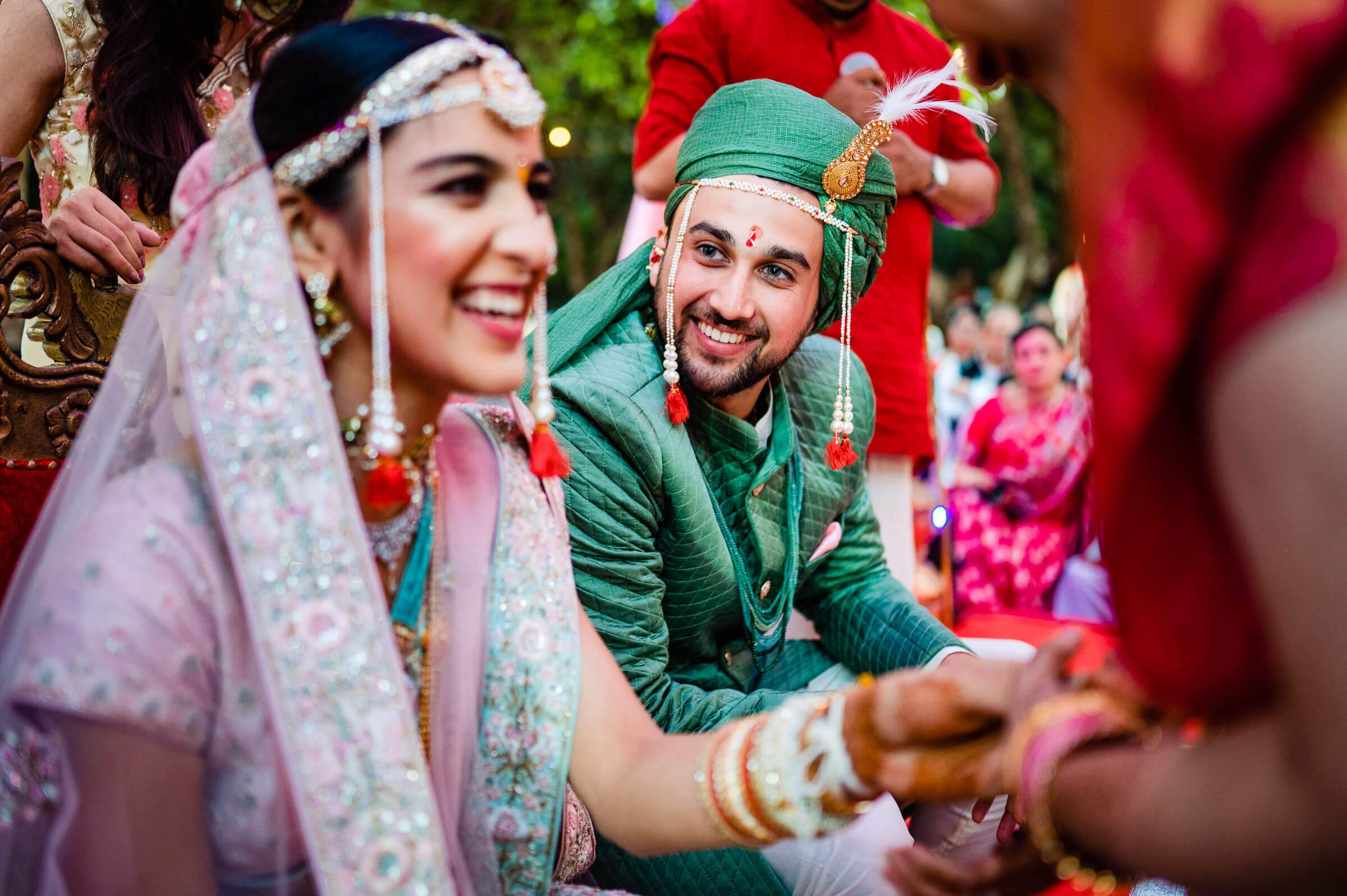 Shreya and Yash smiling in traditional wedding attire surrounded by pink flowers at Mahabaleshwar ceremony