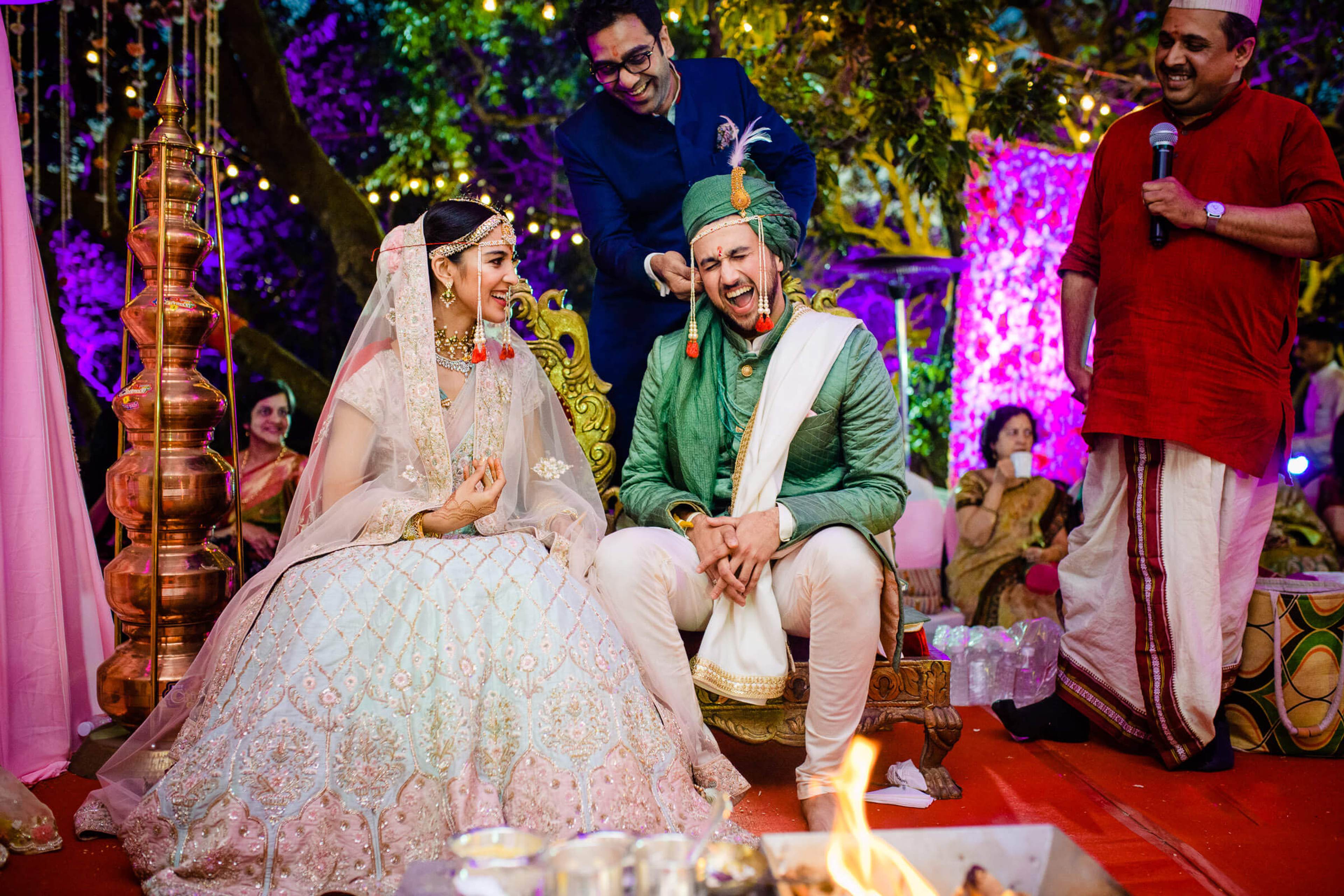 Shreya and Yash laugh together at their vibrant Mahabaleshwar wedding celebration, surrounded by colorful lights and guests