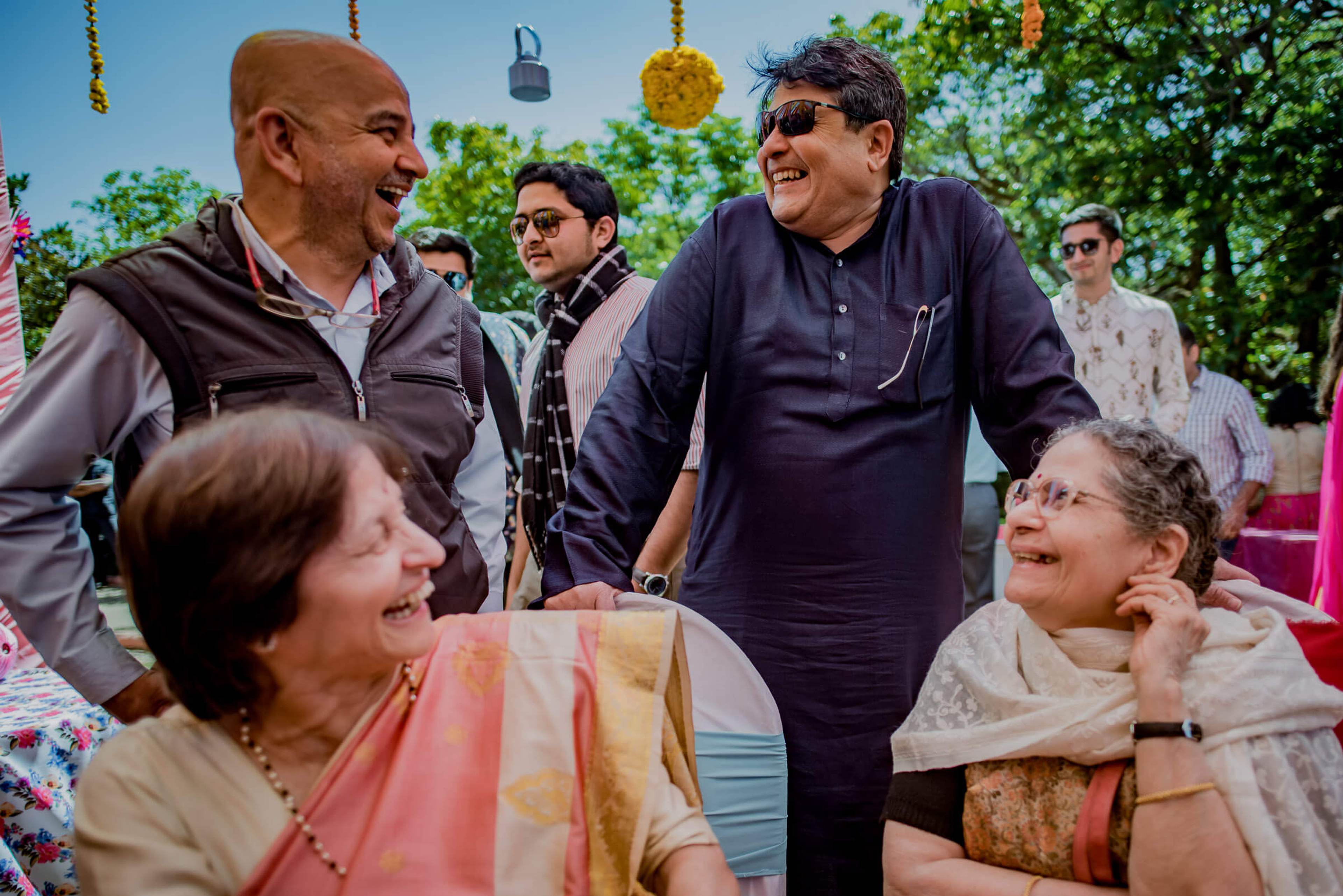 Family and guests laughing together at outdoor celebration with hanging décor and greenery in Mahabaleshwar