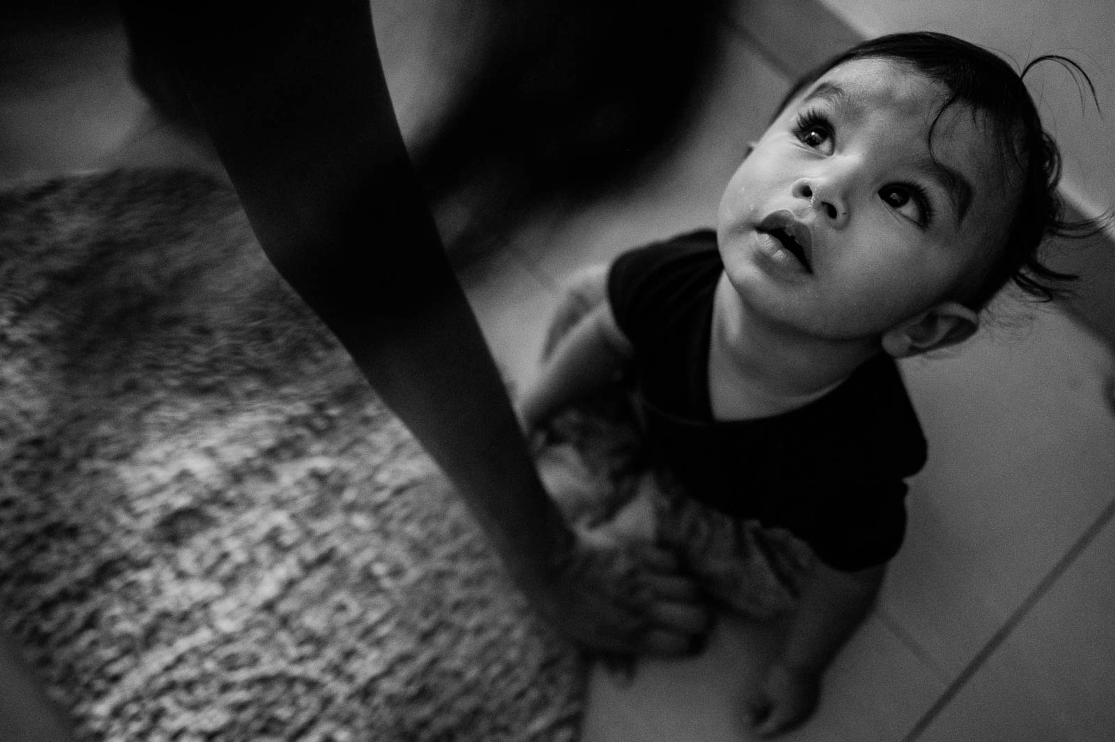 Young child looking upward in black and white portrait, intimate overhead angle