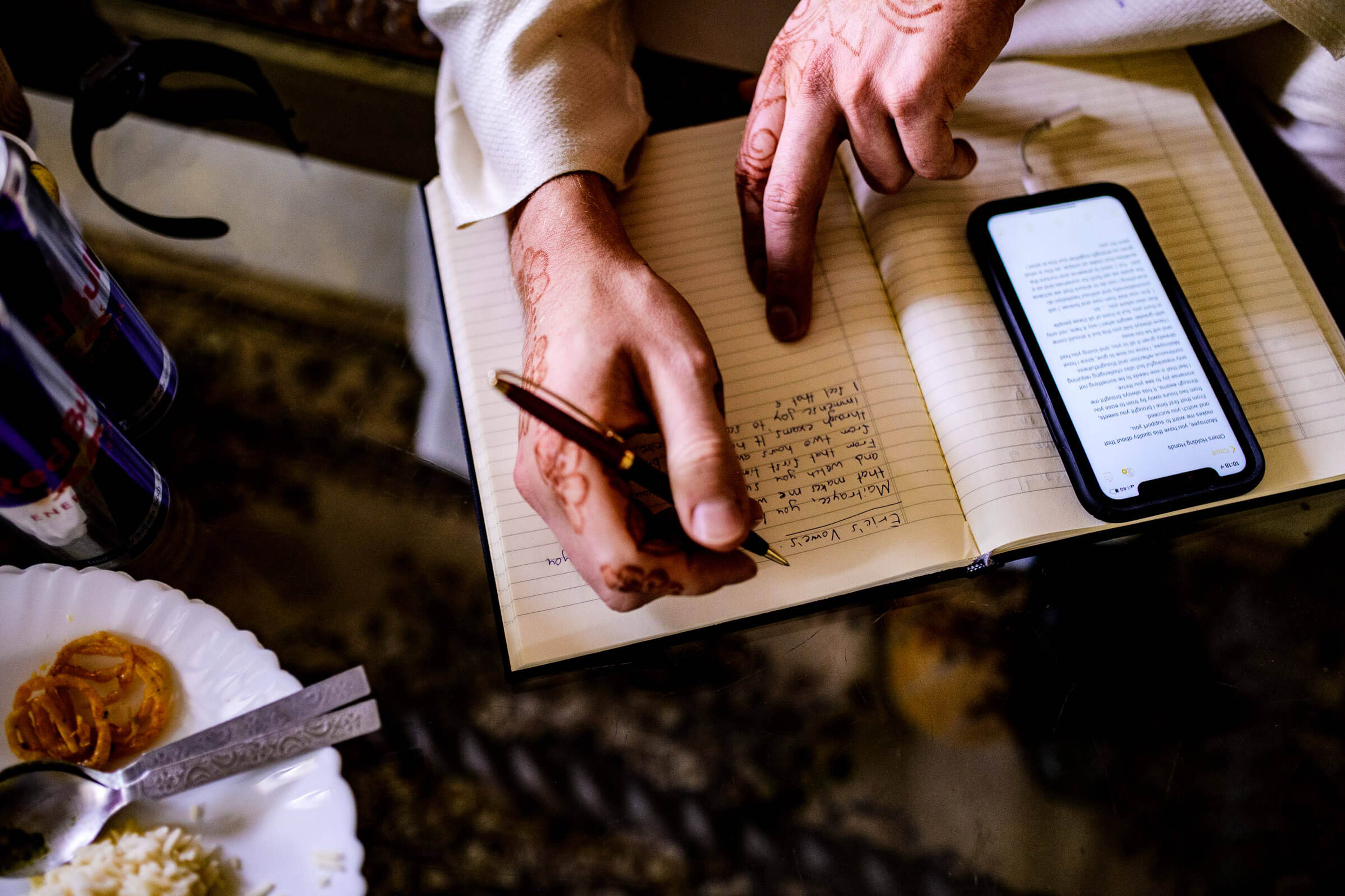 Maitrayee and Eric's hands over handwritten vows and phone in Rajasthan