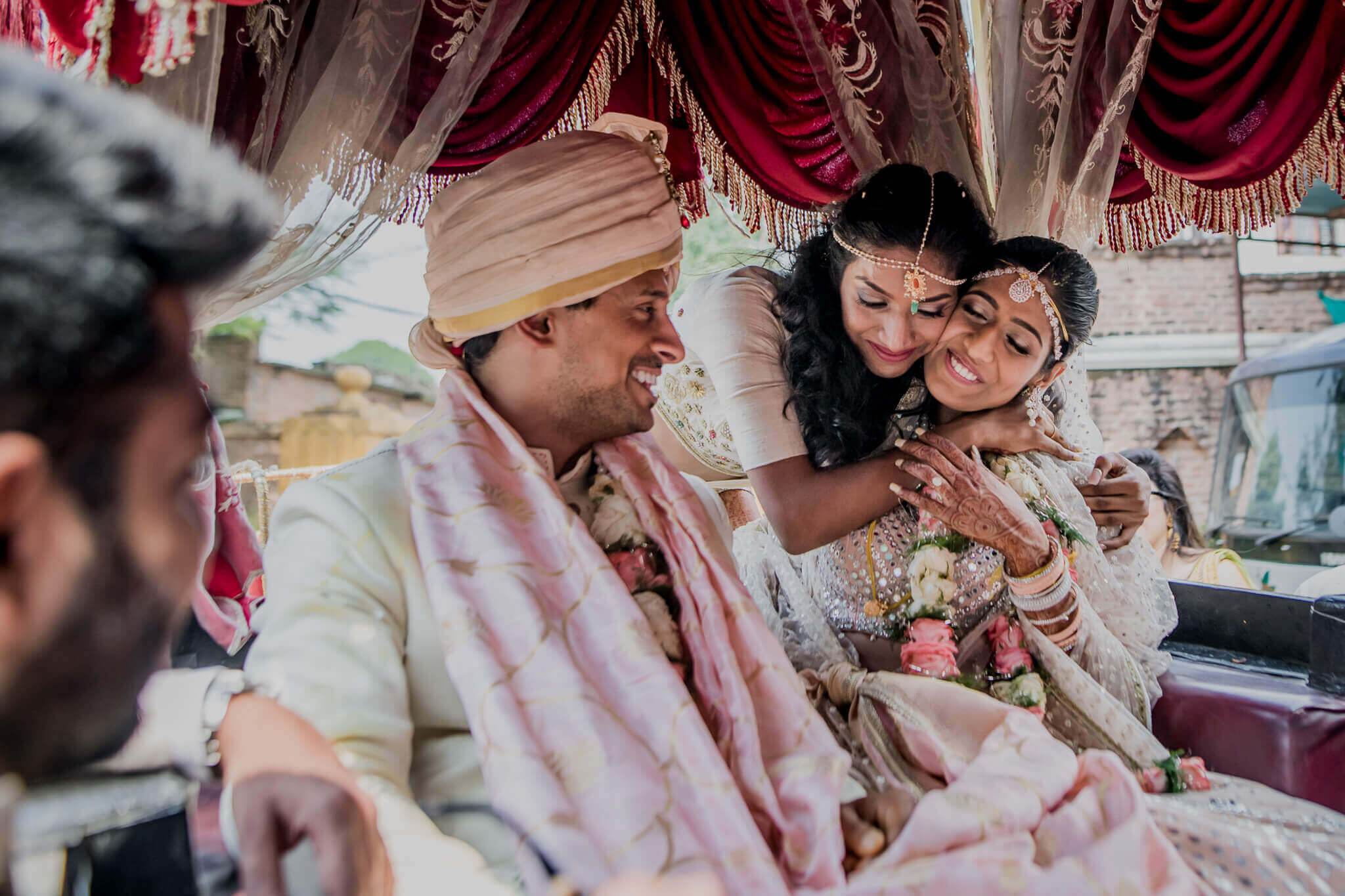 Anu and Raghu smile together under ornate red drapes at their Nepal wedding ceremony, dressed in traditional attire
