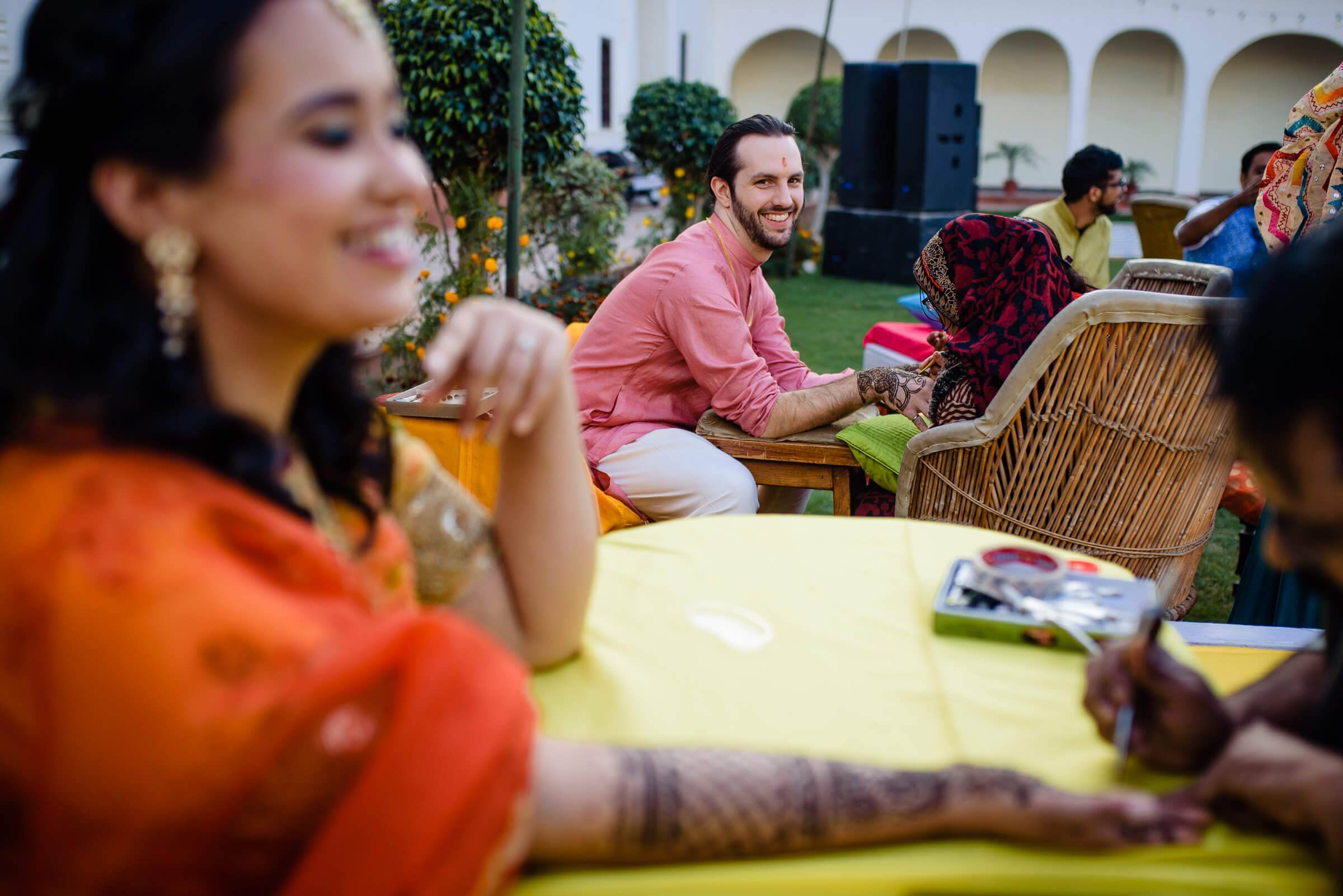 Maitrayee and Eric's guests celebrate outdoors in Rajasthan, seated at yellow tables near arched architecture
