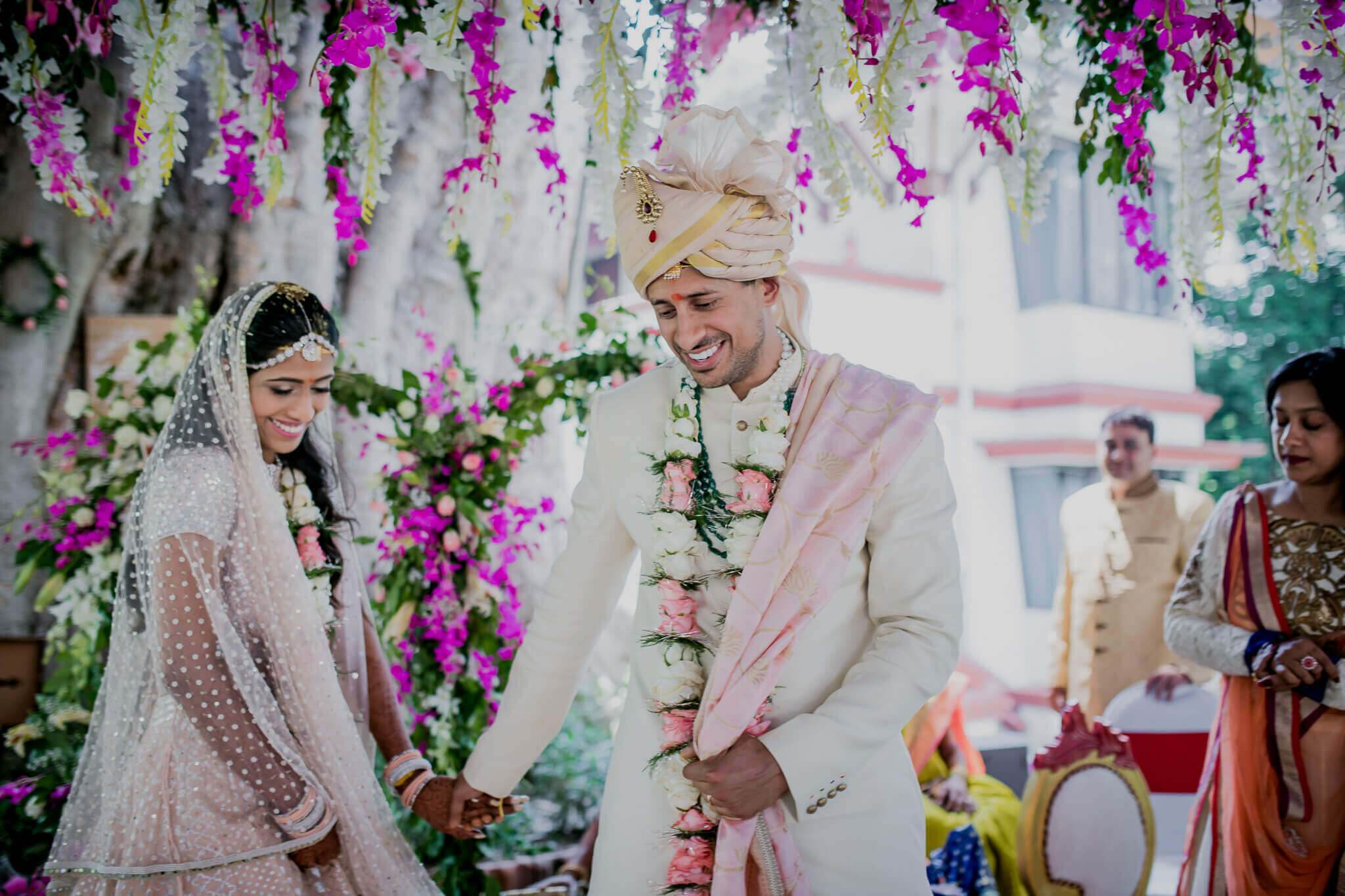 Anu and Raghu exchange smiles under vibrant magenta hanging flowers during their wedding ceremony in Nepal