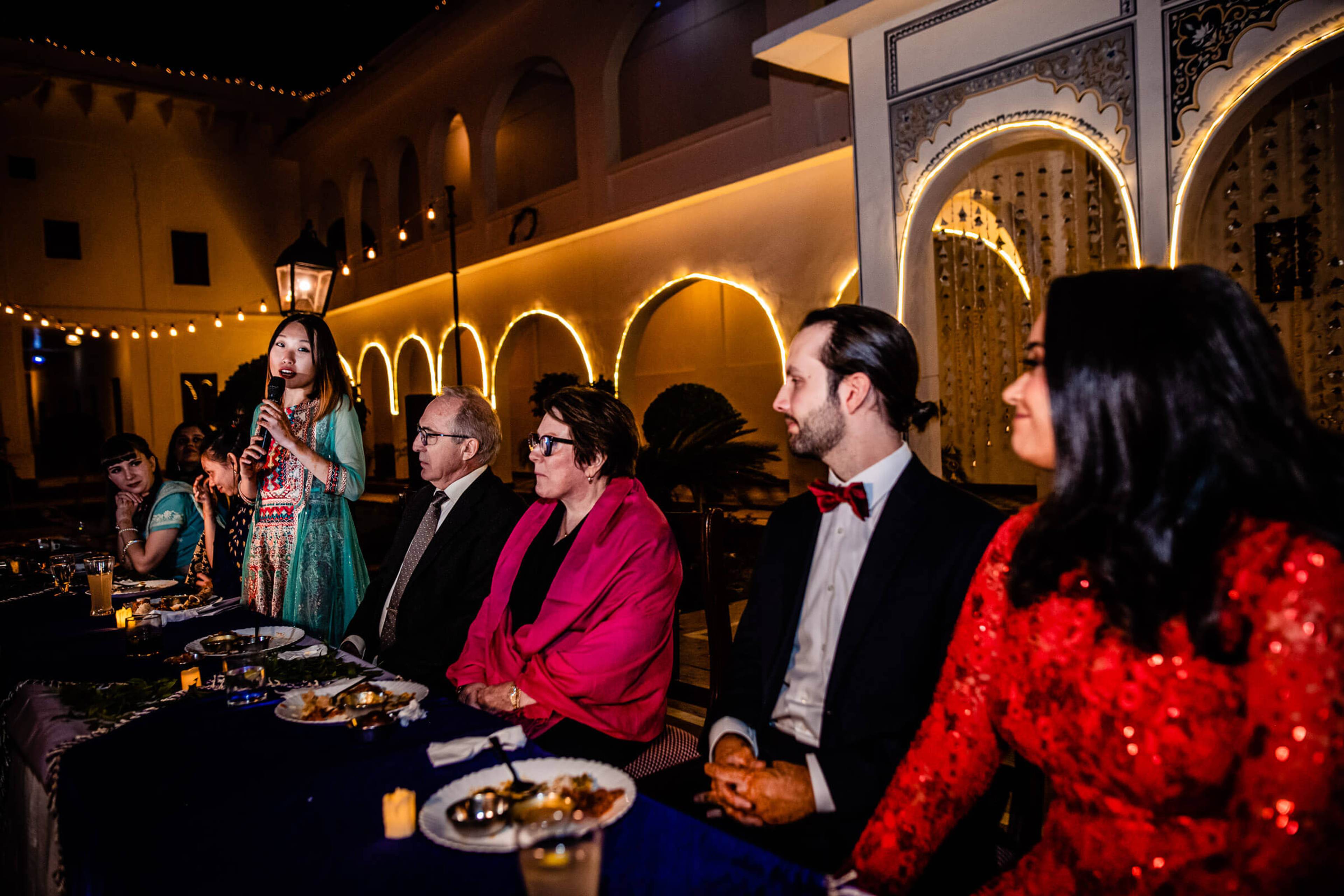 Guests seated at candlelit reception dinner in illuminated Rajasthani courtyard with arched architecture