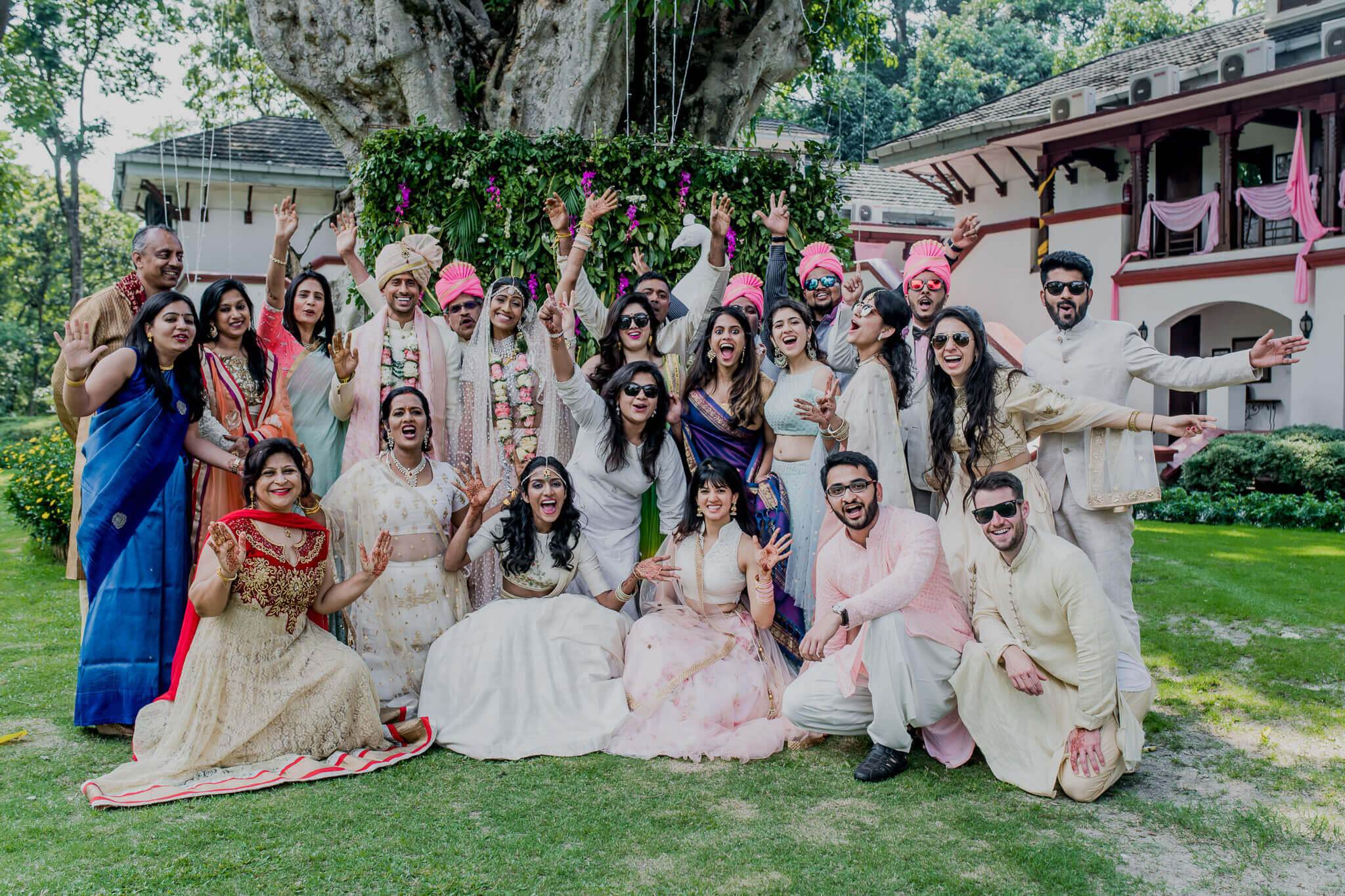 Anu and Raghu's wedding party in cream and pink attire celebrating on Nepal's green lawn