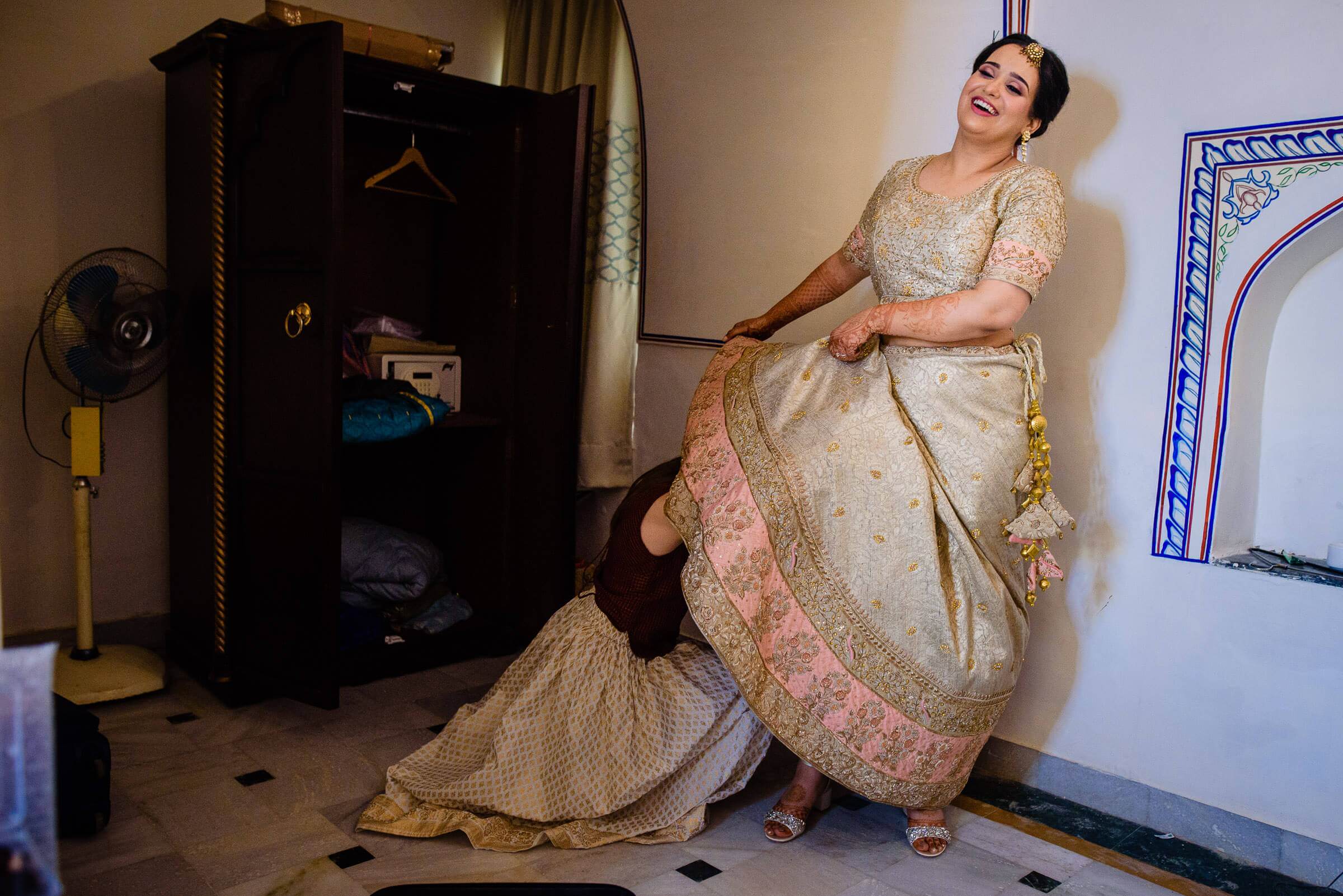 Maitrayee in embroidered traditional dress adjusting her sari, with Eric on the floor in Rajasthan
