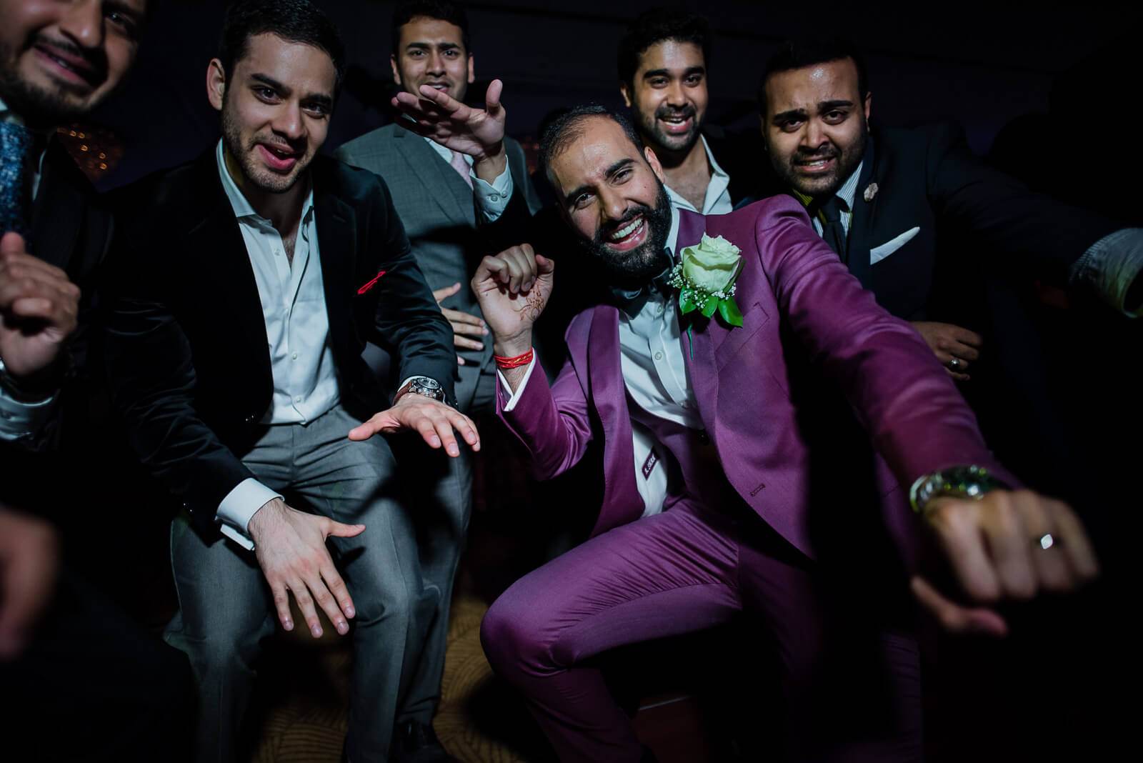 Groom Ankit in purple suit celebrating with groomsmen in New York, nighttime reception