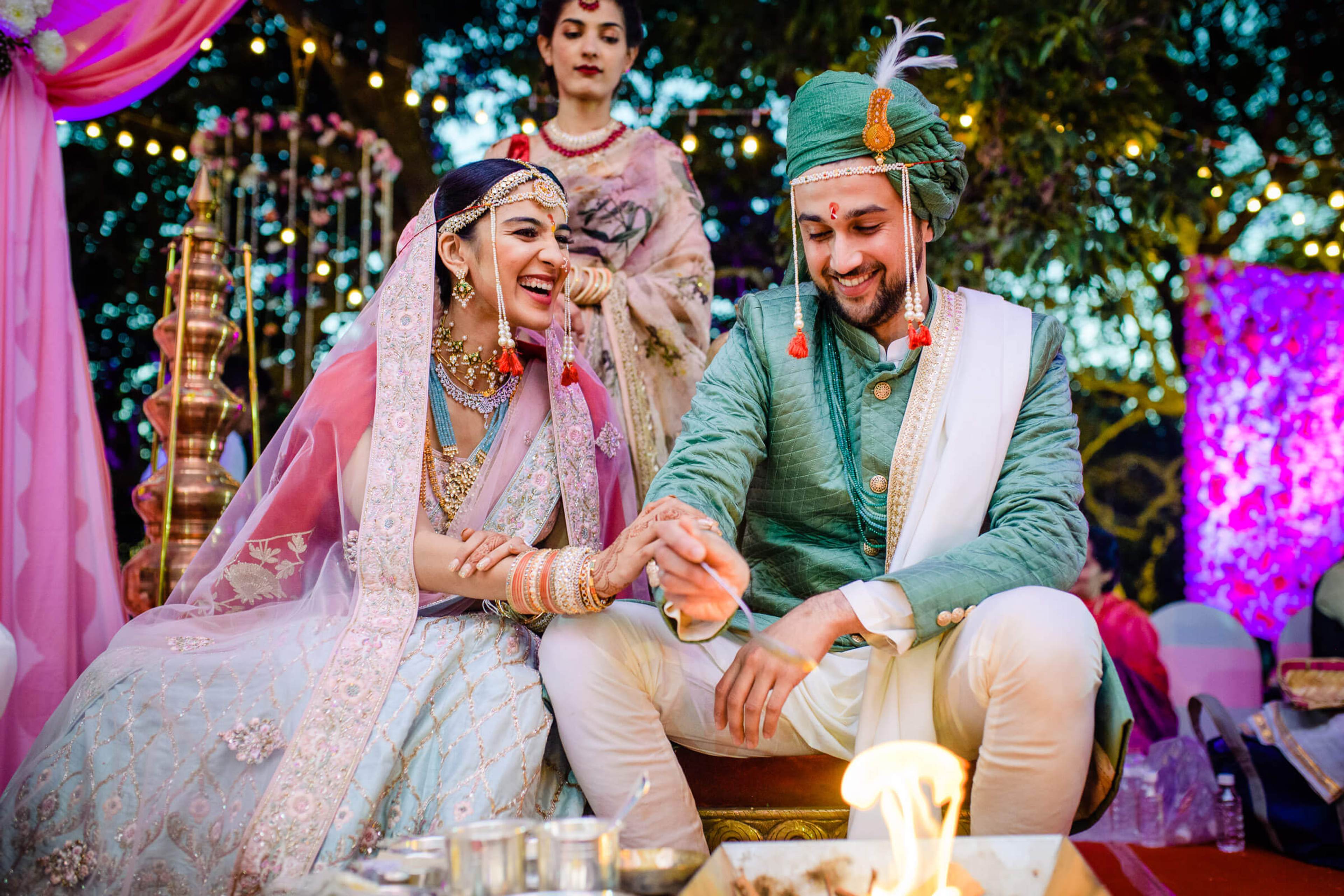 Shreya and Yash holding hands at their Mahabaleshwar wedding reception under twinkling lights and pink décor