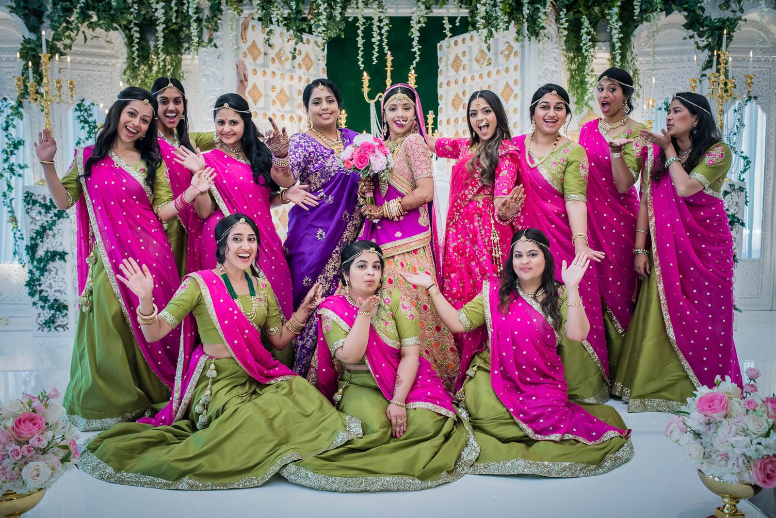 Barkha & Ankit's bridal party in vibrant pink and green traditional attire, posed together at New York celebration