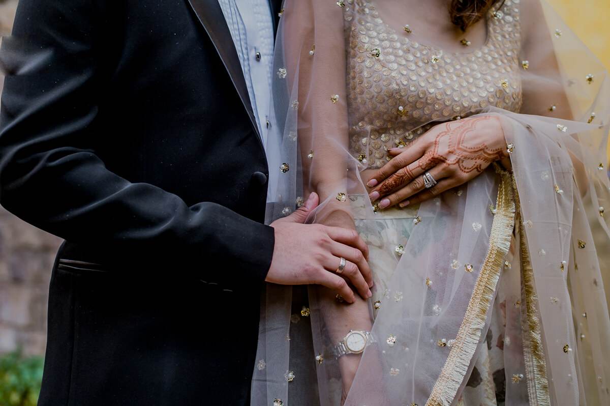 Shreya and Yash's hands together, beaded gold dupatta, black suit, wedding rings visible at Mahabaleshwar