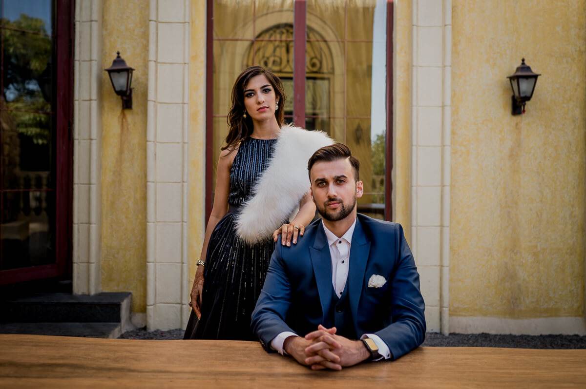 Shreya and Yash pose elegantly outside a yellow stone facade with lanterns in Mahabaleshwar