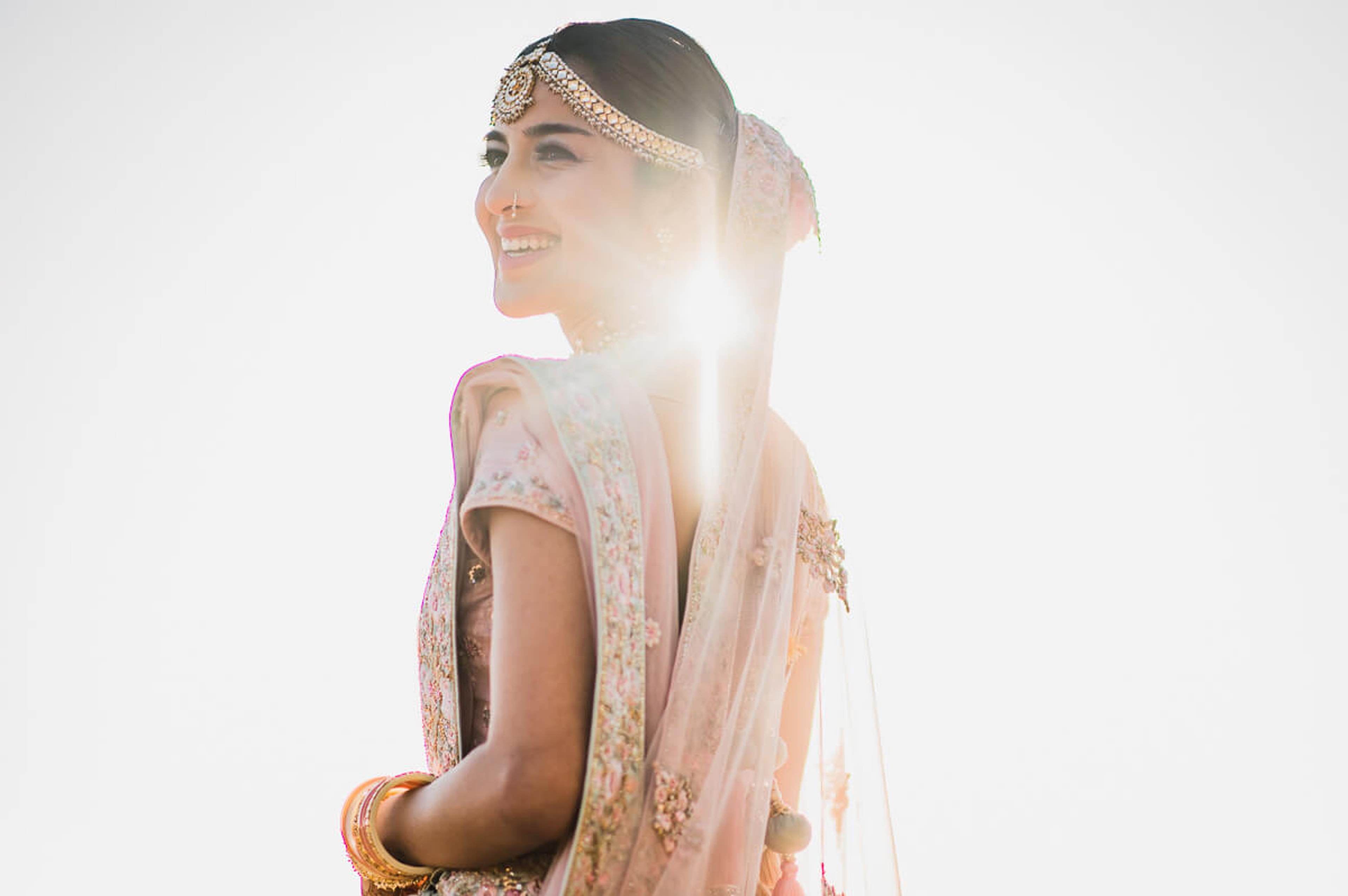 Shreya in ornate pink lehenga with jeweled headpiece, backlit by golden sunlight