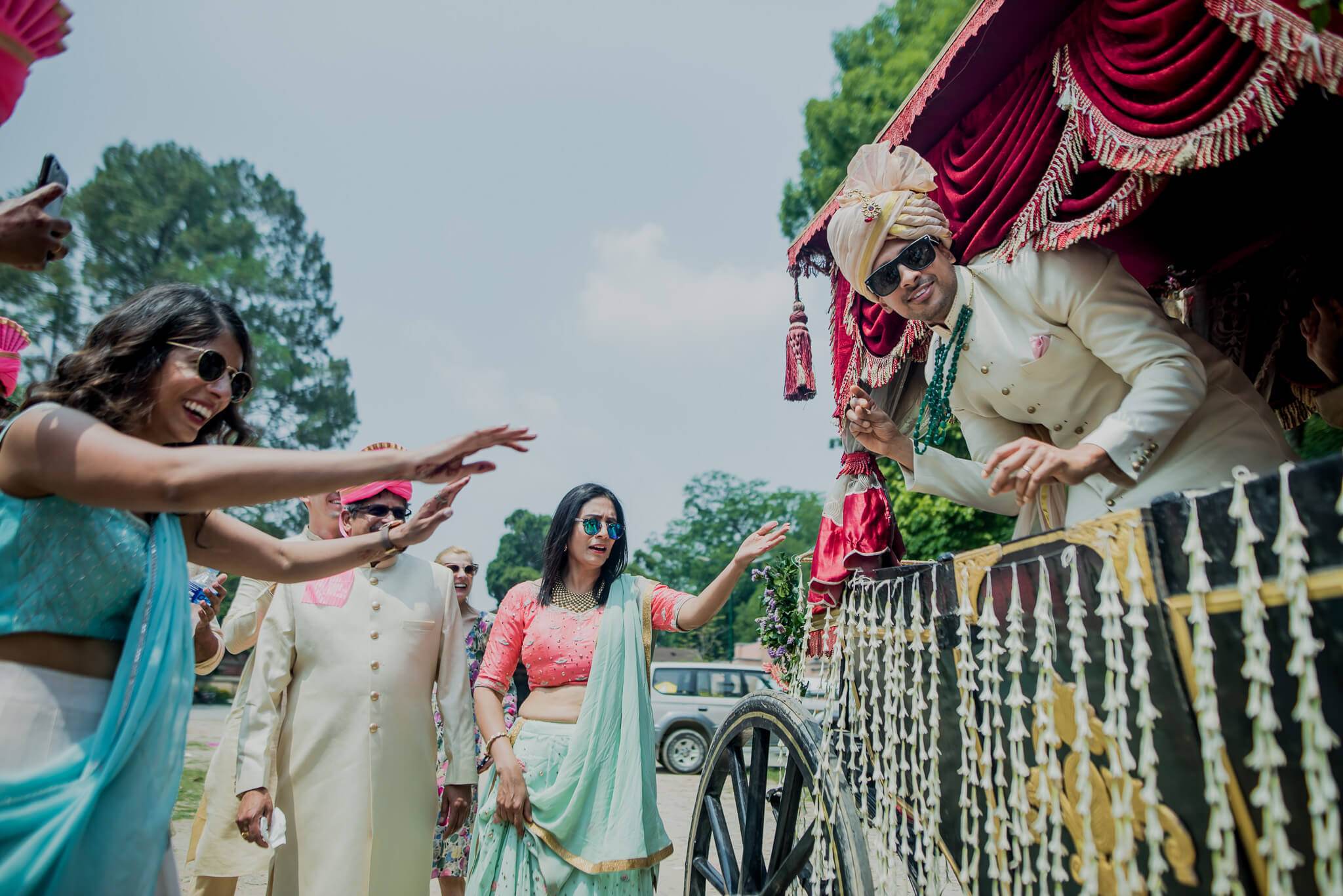 Anu and Raghu celebrate with guests in traditional attire under a red draped canopy in Nepal