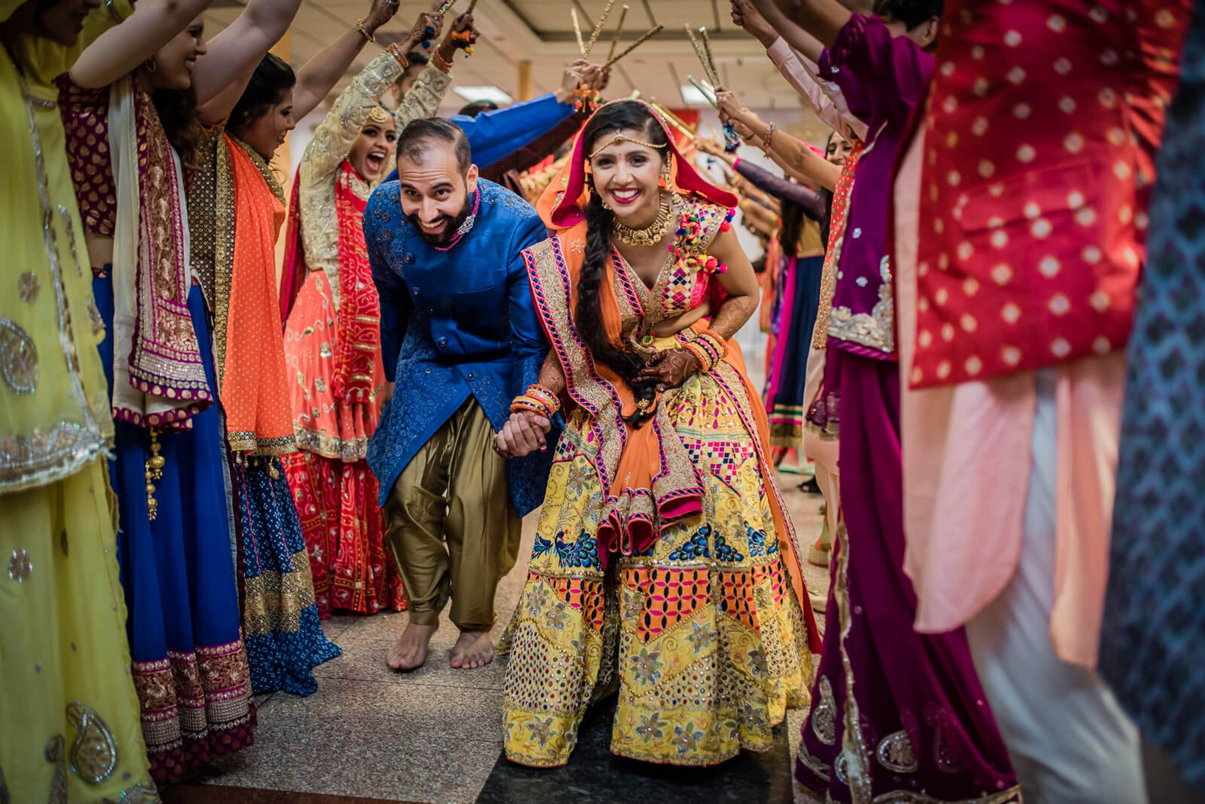Barkha and Ankit in traditional Indian wedding attire surrounded by colorful fabrics and garments in New York