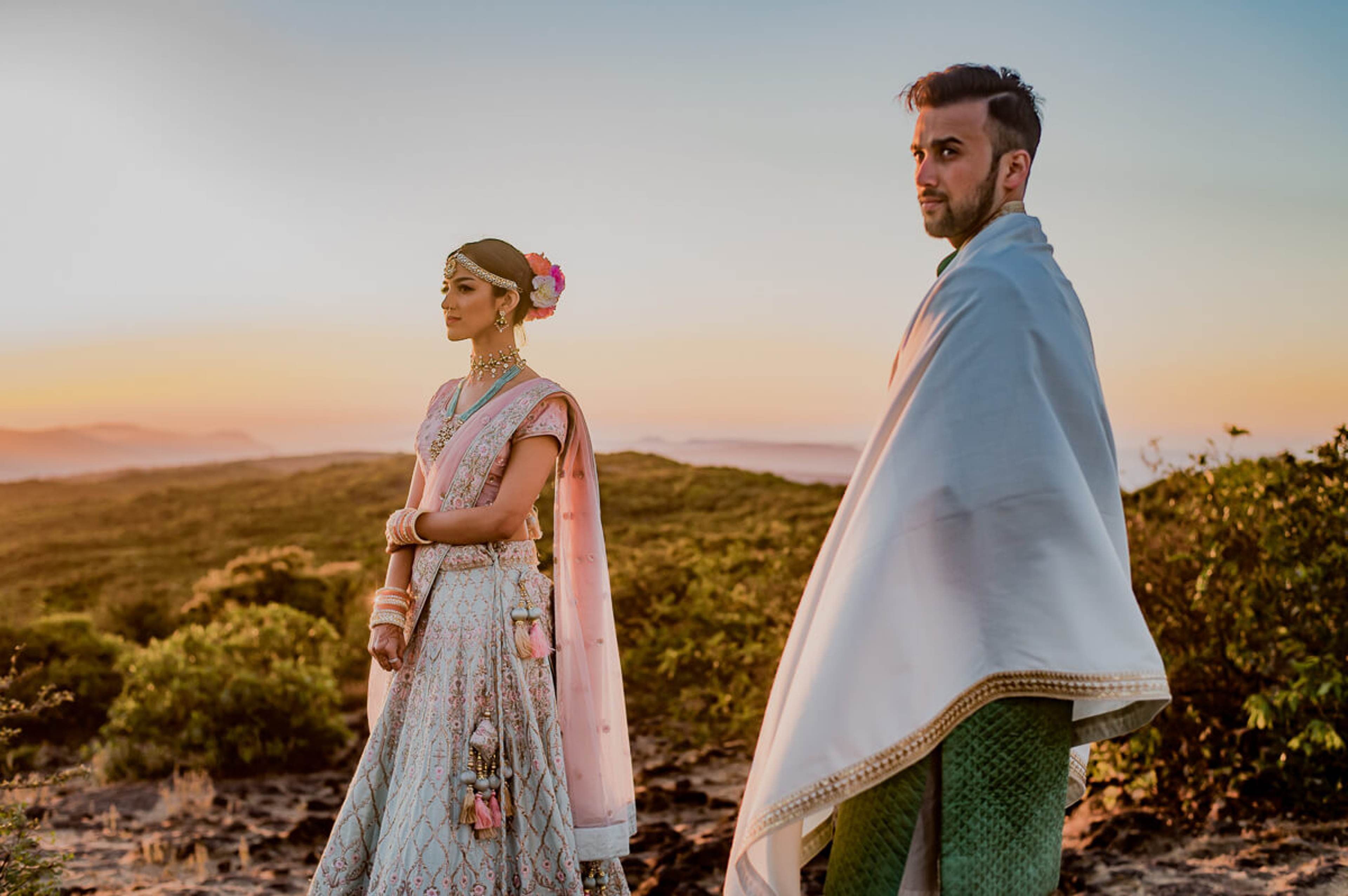 Shreya and Yash stand on a Mahabaleshwar hilltop at sunset, wrapped in flowing fabrics, golden light behind them