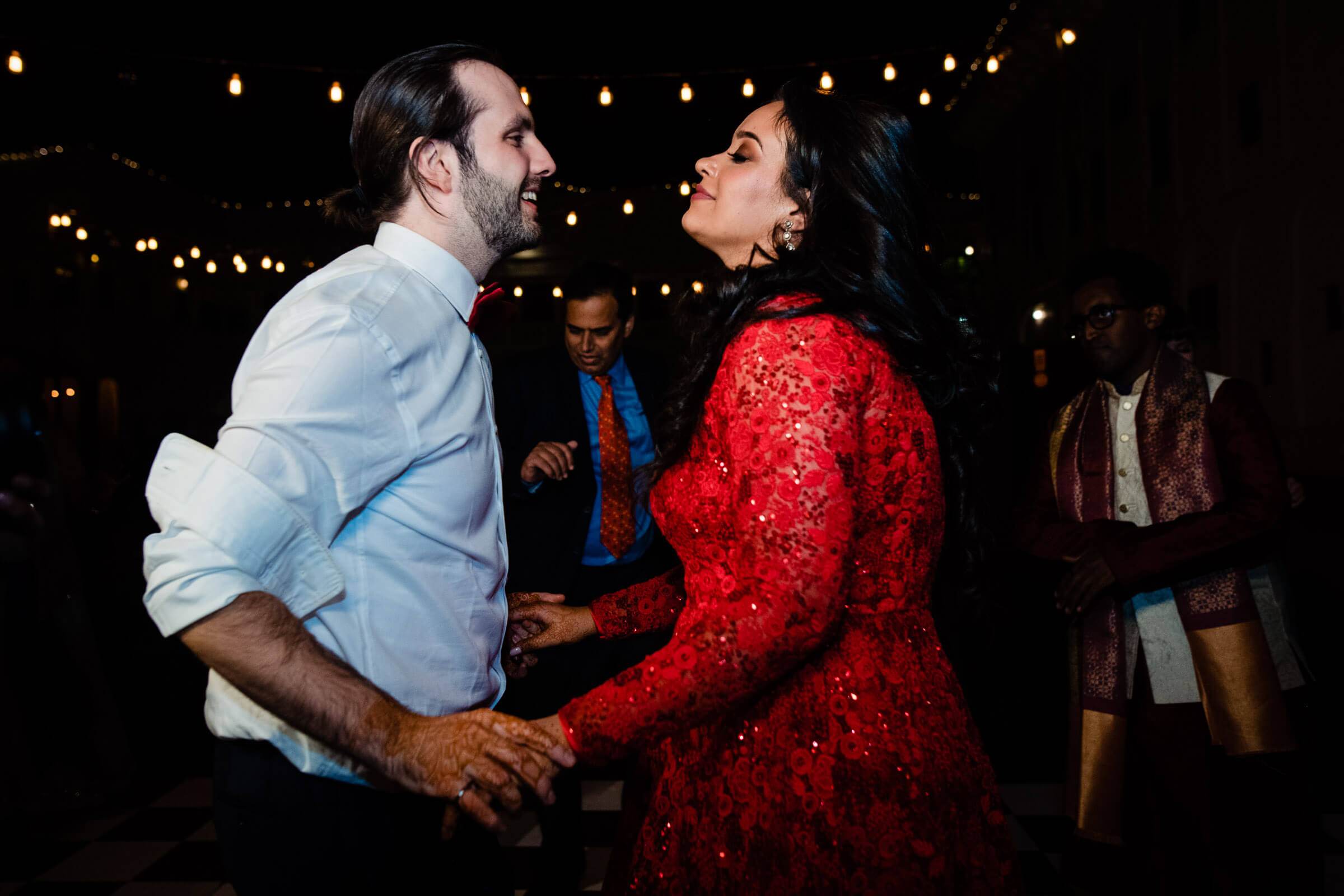Maitrayee in red sequin dress and Eric in light blue shirt dance under twinkling lights at Rajasthan celebration